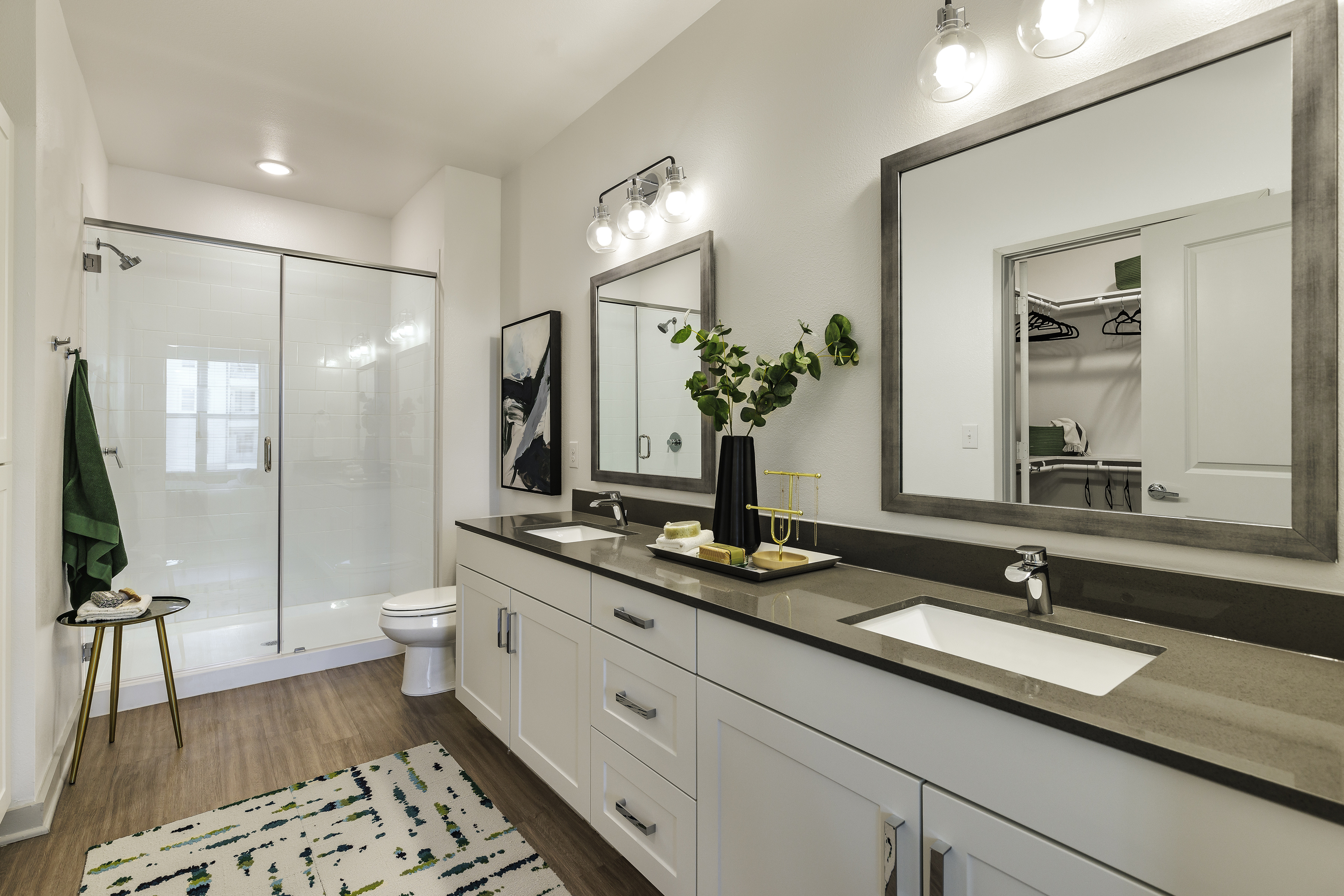 Luxurious modern bathroom with dual sinks, large mirror, and glass-enclosed shower.