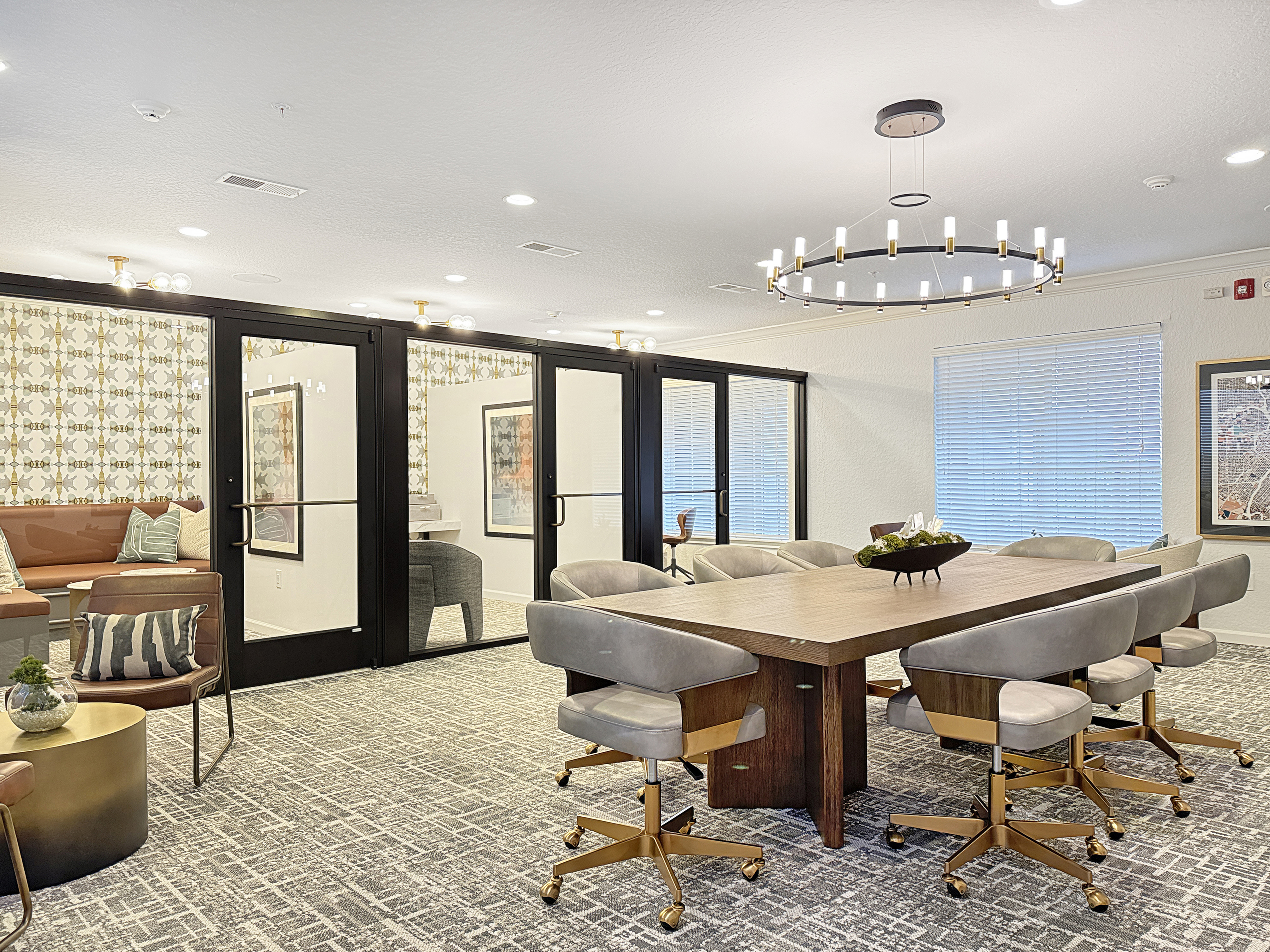 Elegant communal space with modern chandeliers, plush seating, and large conference table, ideal for meetings or social gatherings.
