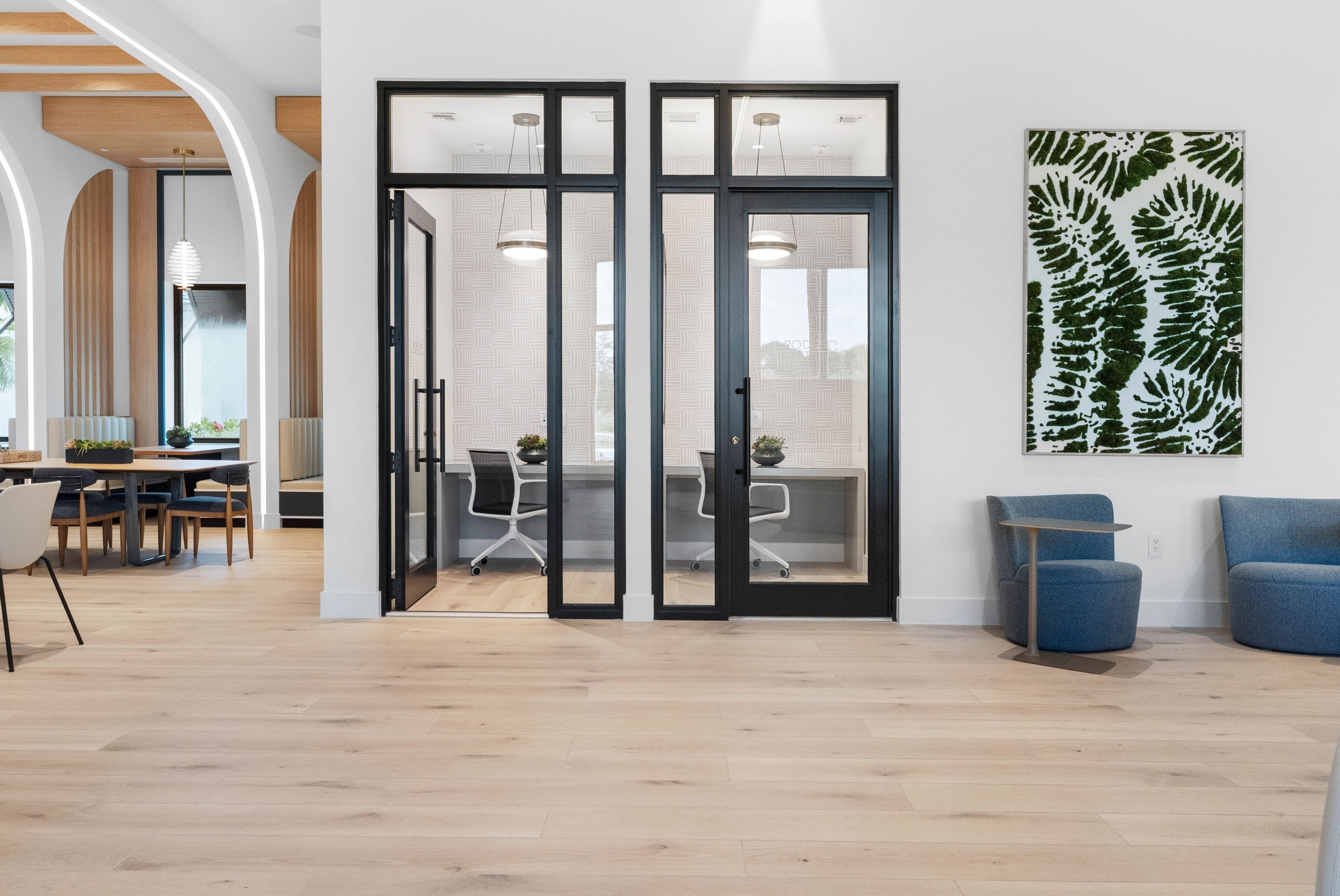 Contemporary open space with meeting rooms, stylish seating, and elegant wooden accents.