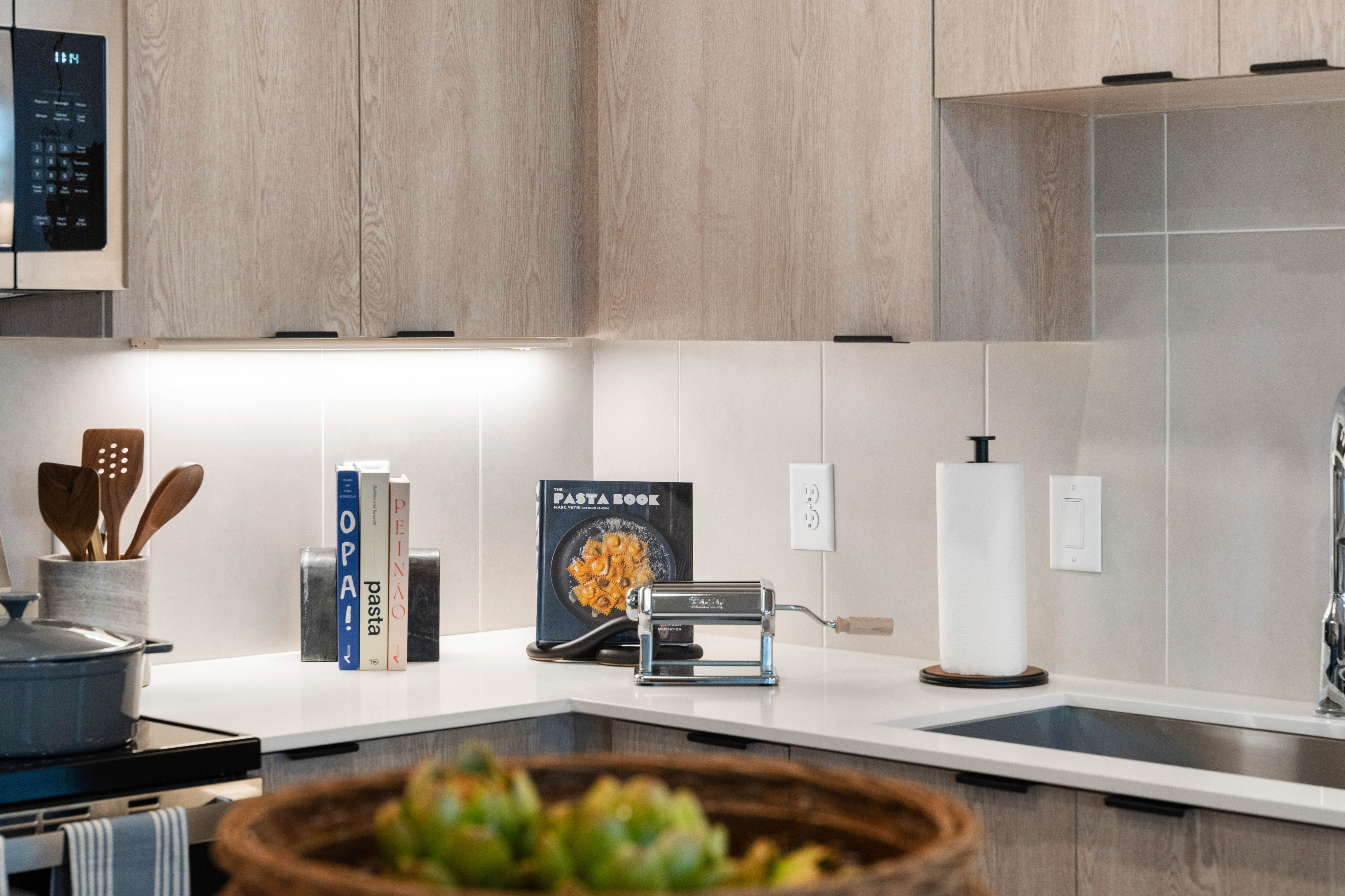 Chic modern kitchen with wooden cabinets, sleek countertops, and a pasta-making station, ideal for culinary enthusiasts.