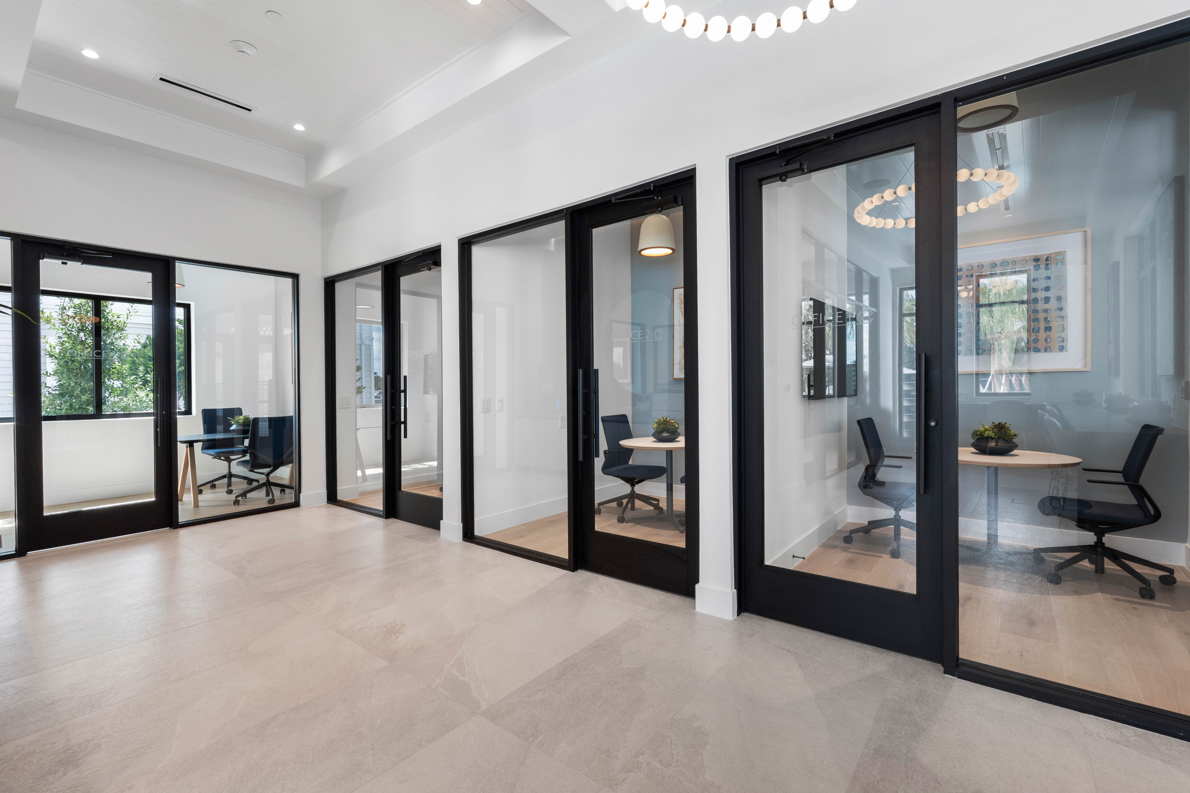 Modern office space with sleek glass-enclosed meeting rooms and stylish decor offering a bright and professional environment.