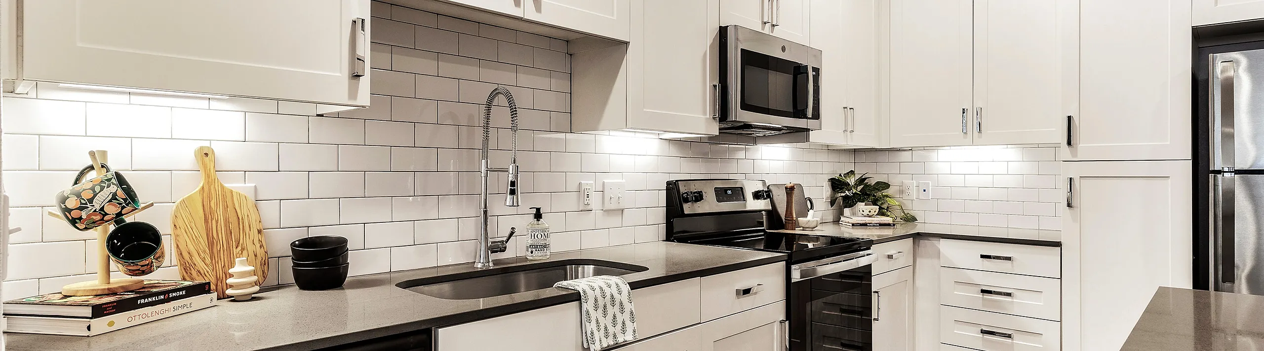 Contemporary kitchen with white cabinets, stainless steel appliances, and a stylish tile backsplash.