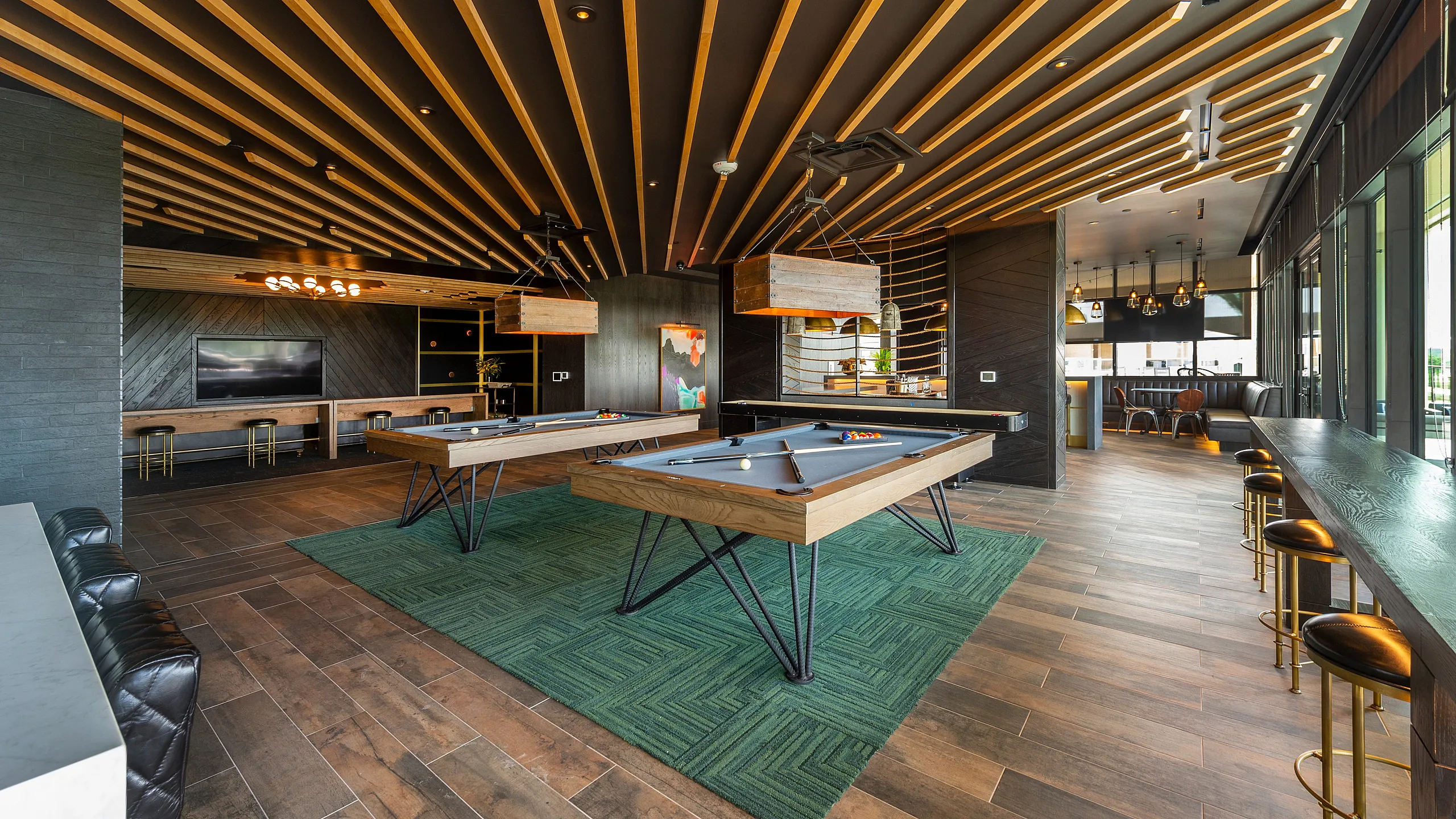 Chic recreational room with pool tables, stylish bar seating and modern lighting.