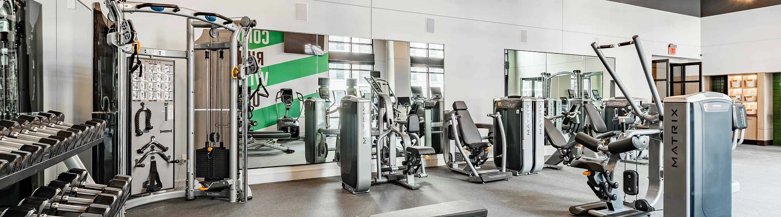 Modern gym with state-of-the-art equipment, including weights and cardio machines, under stylish lighting fixtures.