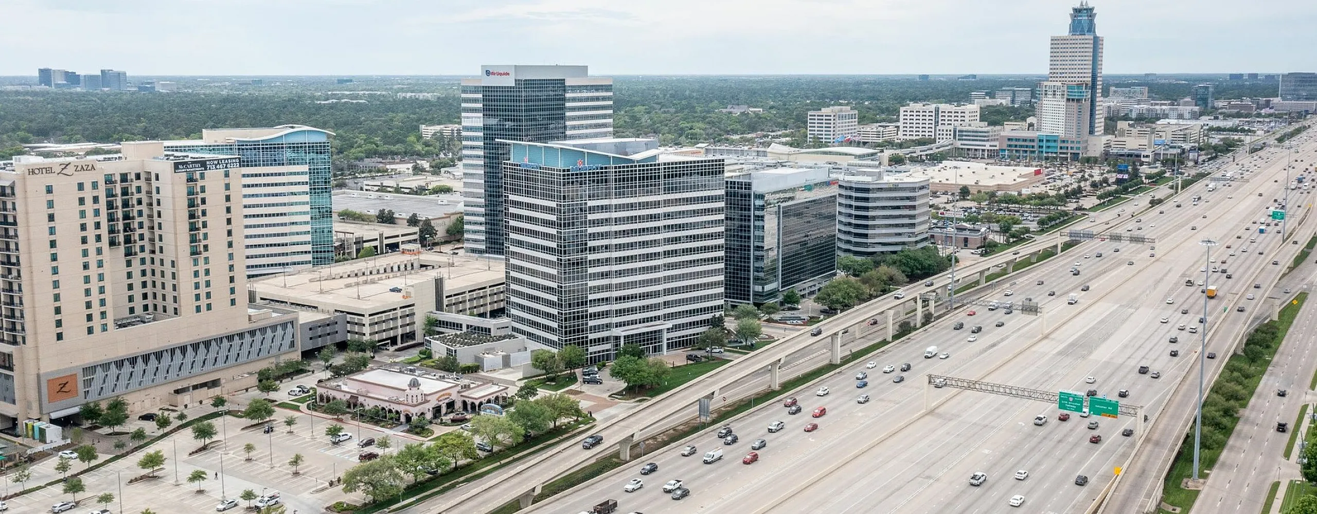 Expansive cityscape showcasing modern office buildings adjacent to a major highway.