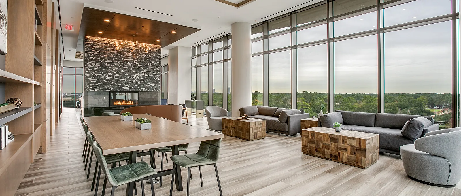 Spacious modern lounge area with large windows, stylish furniture, and a stunning fireplace centerpiece.