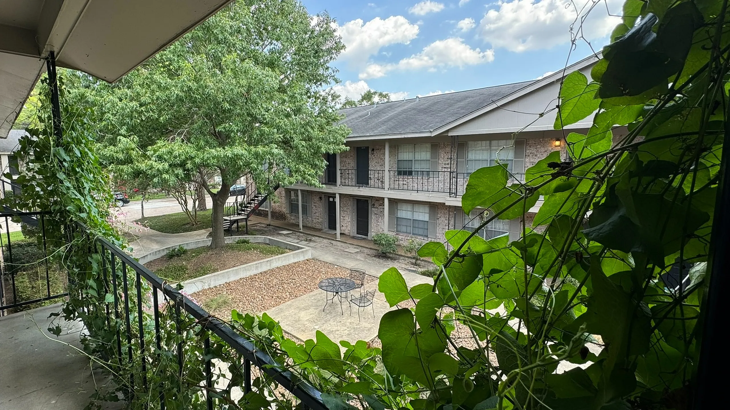 Charming apartment courtyard with lush greenery and cozy seating area.