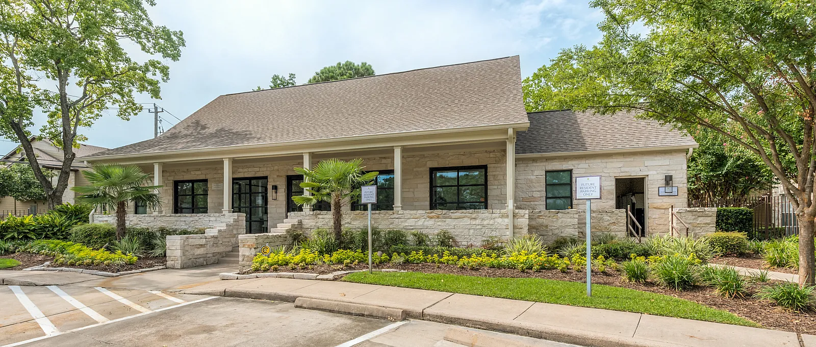 Charming stone building with lush landscaping and a welcoming entrance under a clear sky.