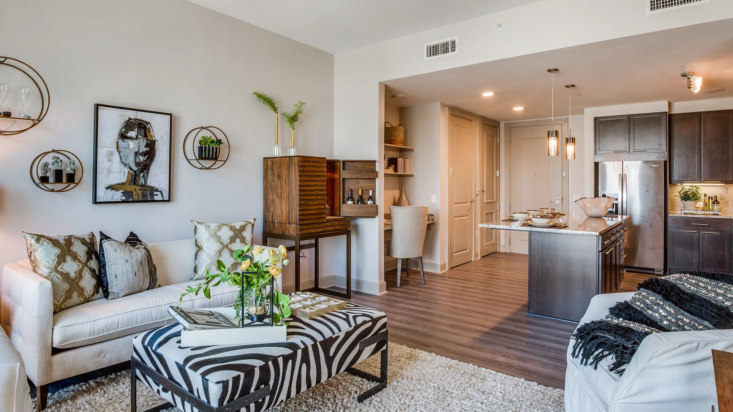 Bright modern living space featuring elegant furniture, stylish decor, and an open-concept kitchen with sleek dark cabinets.