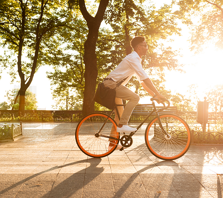Vibrant morning scene of a person enjoying a sunrise bike ride through a lush park with glowing sunlight.