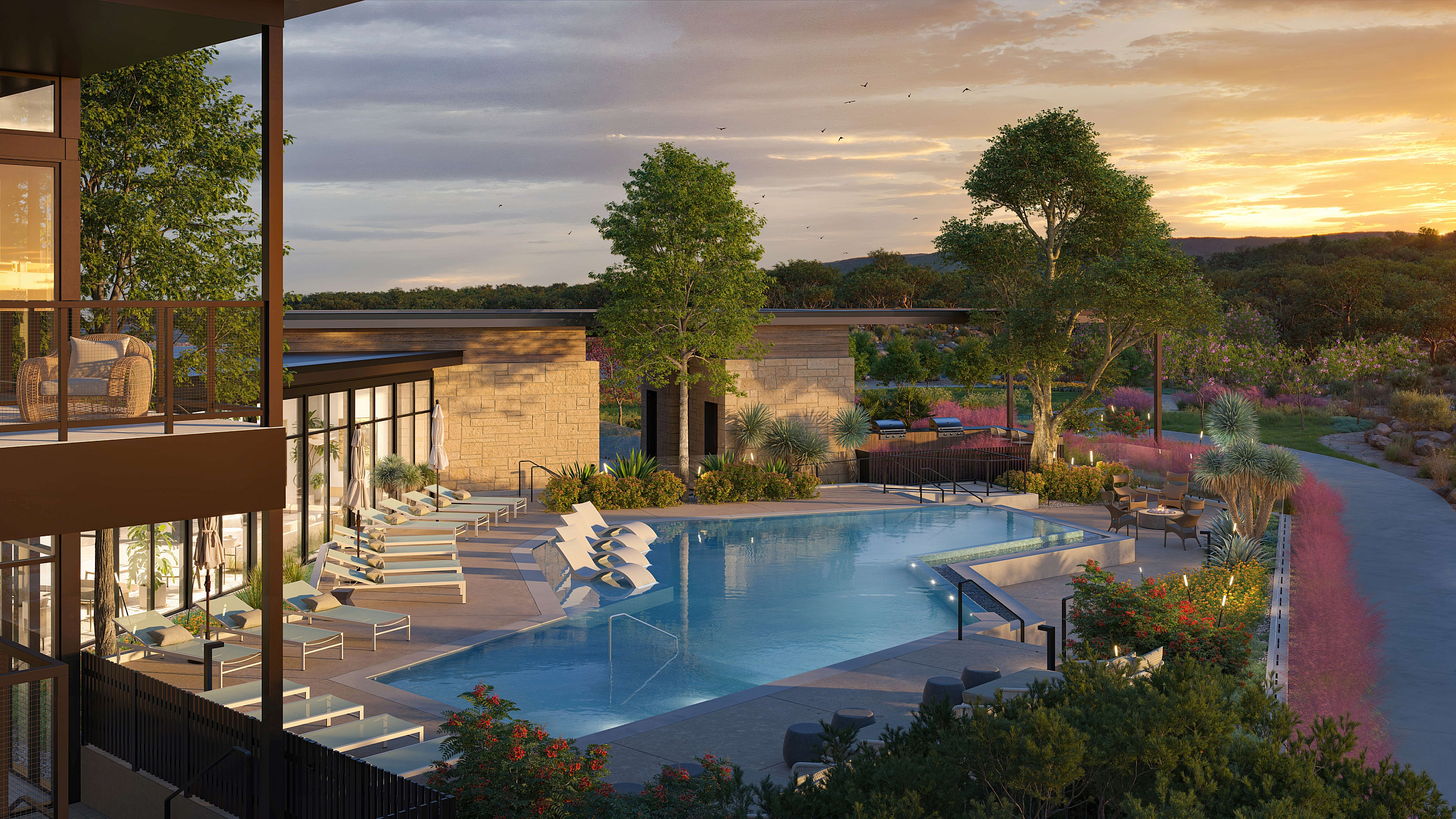 Luxurious outdoor pool area with stylish loungers, surrounded by lush greenery and a stunning sunset view.