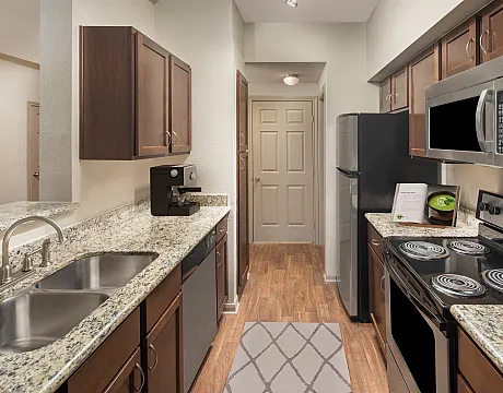 Inviting kitchen with modern appliances, stylish granite countertops, and warm wooden cabinetry, perfect for culinary creativity.