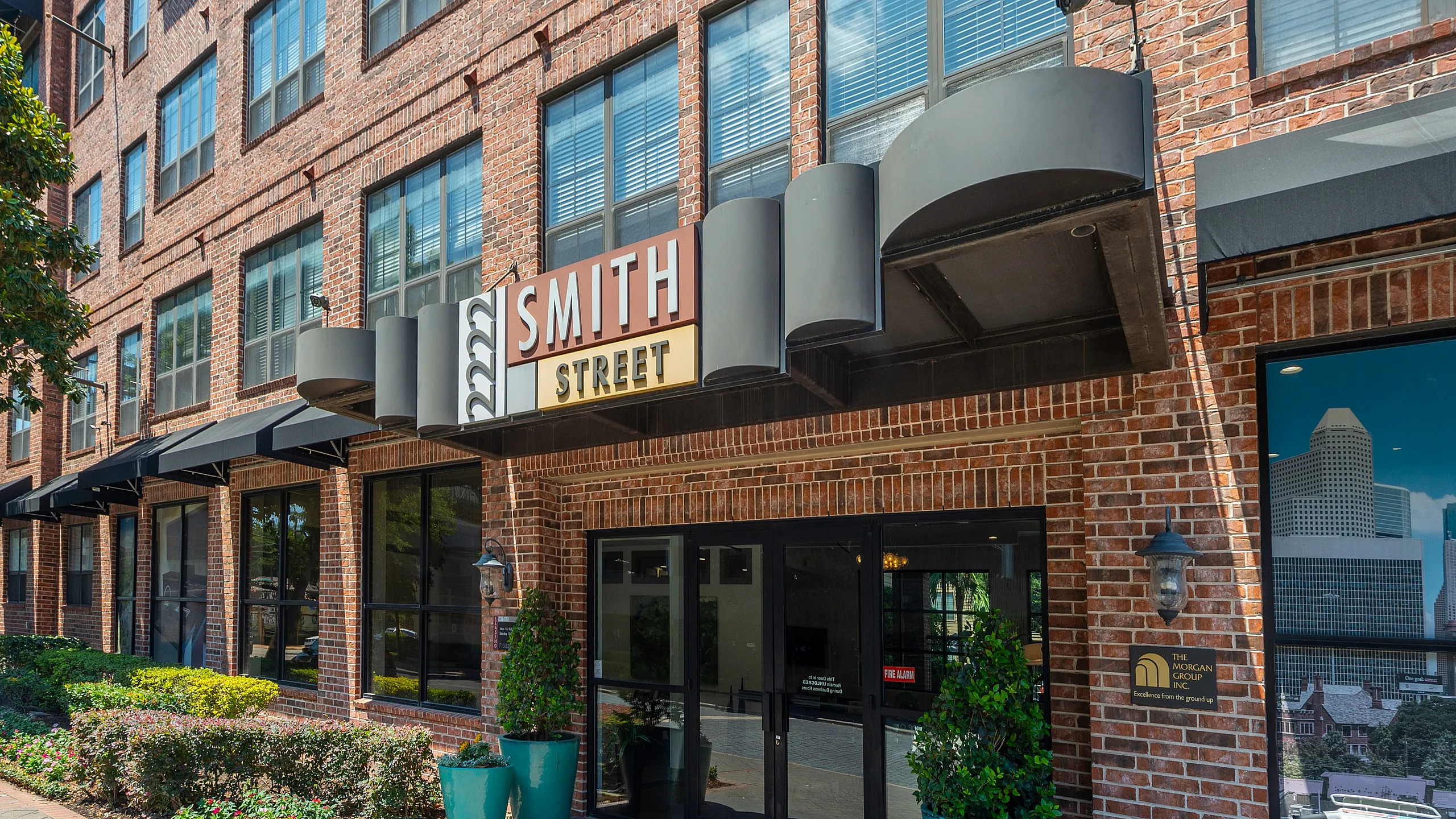 Charming brick exterior of Smith Street apartments featuring modern windows, elegant landscaping, and welcoming entrance.