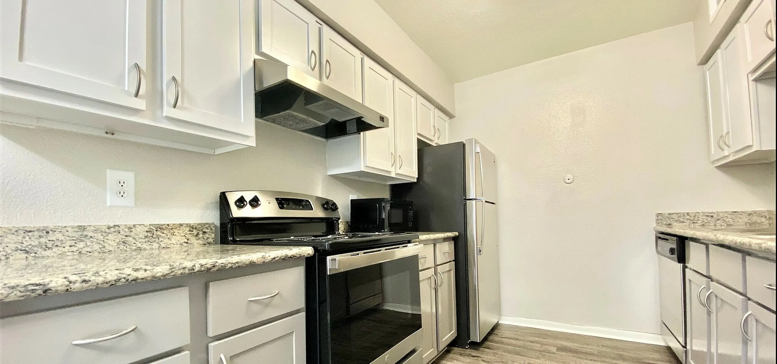 Modern kitchen featuring sleek stainless steel appliances, elegant granite countertops, and ample cabinet space with a bright, ambient glow.