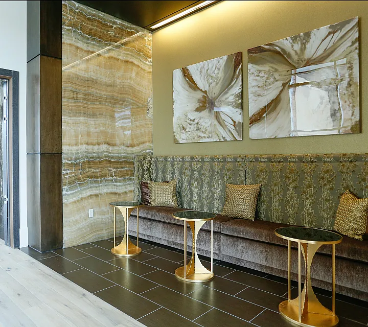 Elegant apartment lobby featuring a luxurious sitting area with plush seating, artistic decor, and contemporary gold accent tables.