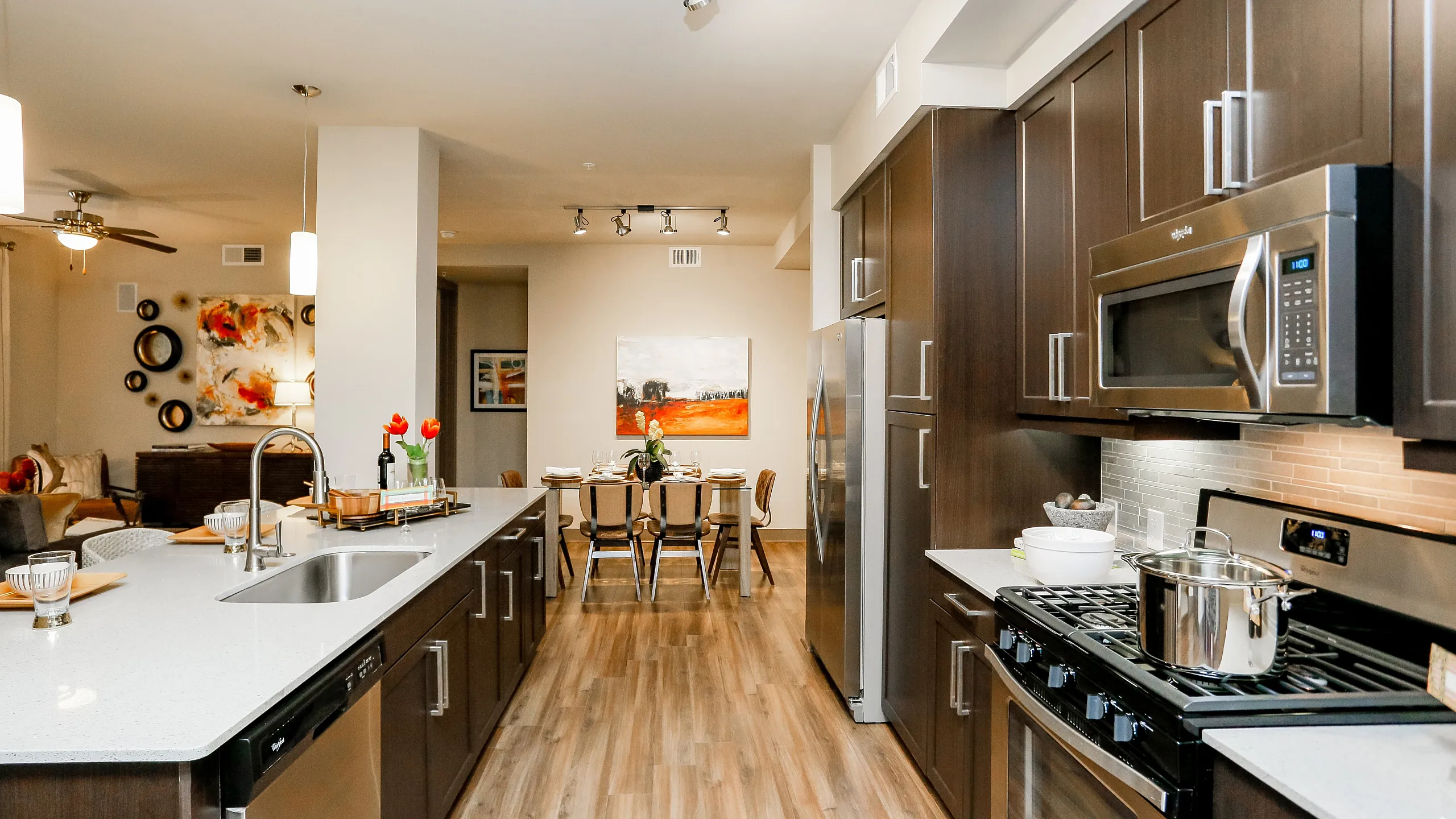 Modern apartment interior showcasing an elegant kitchen with sleek cabinetry, stainless steel appliances, and a spacious island leading to a cozy dining area.