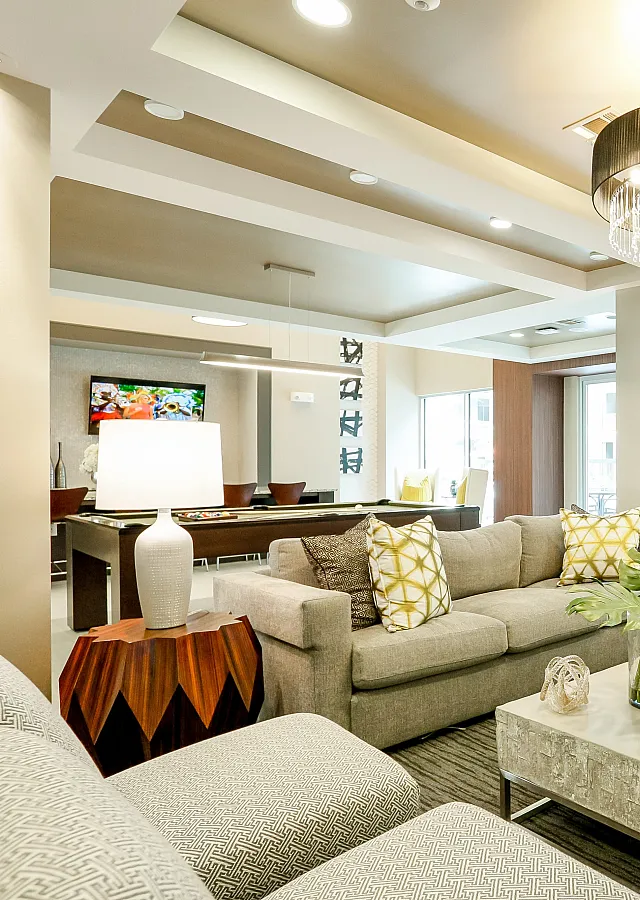 Luxurious living room with modern furniture, a sparkling chandelier, and bright natural light from large windows.