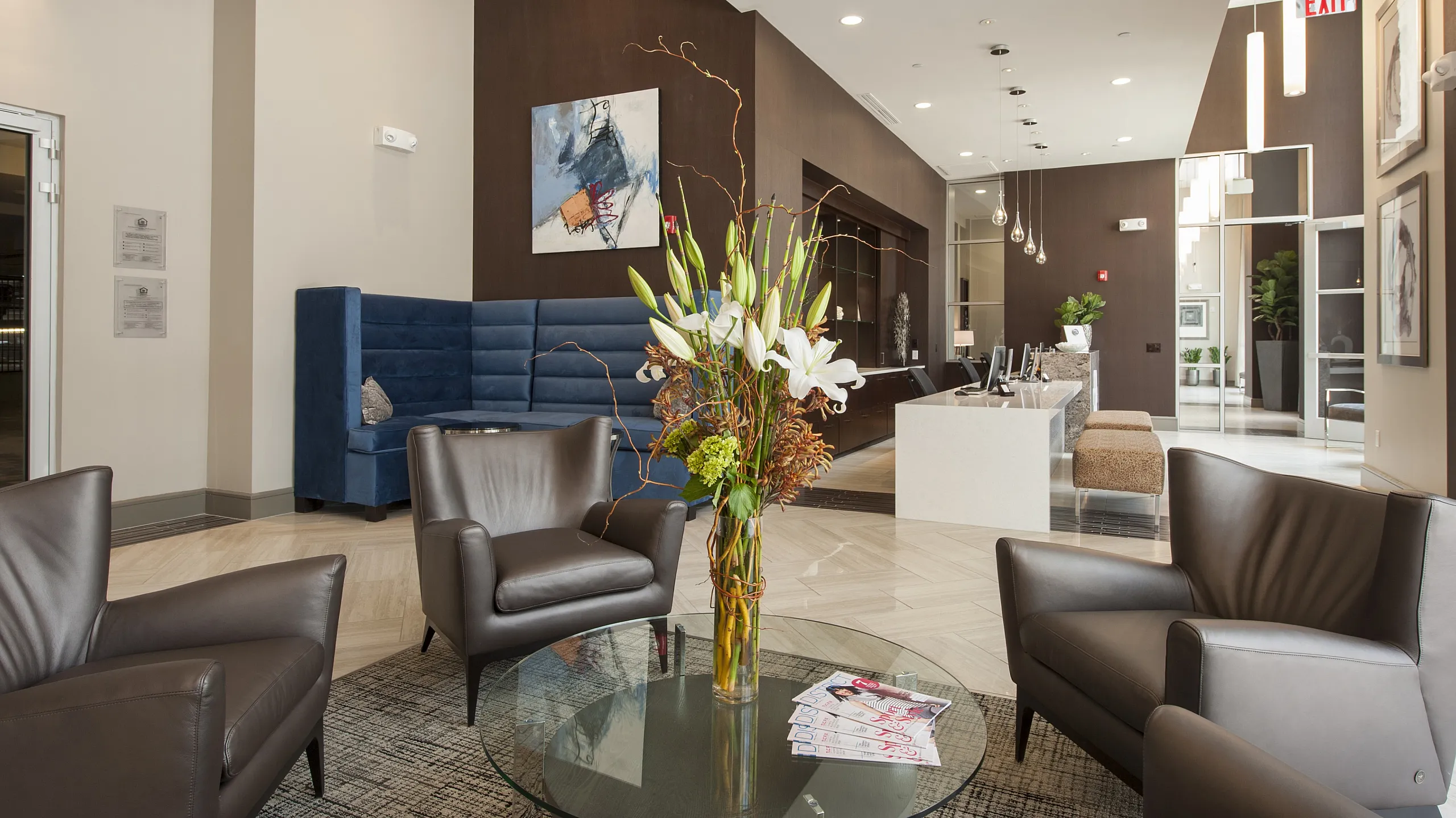Elegant apartment lobby showcasing chic leather seating, a vibrant floral centerpiece, and modern decor under ambient lighting.