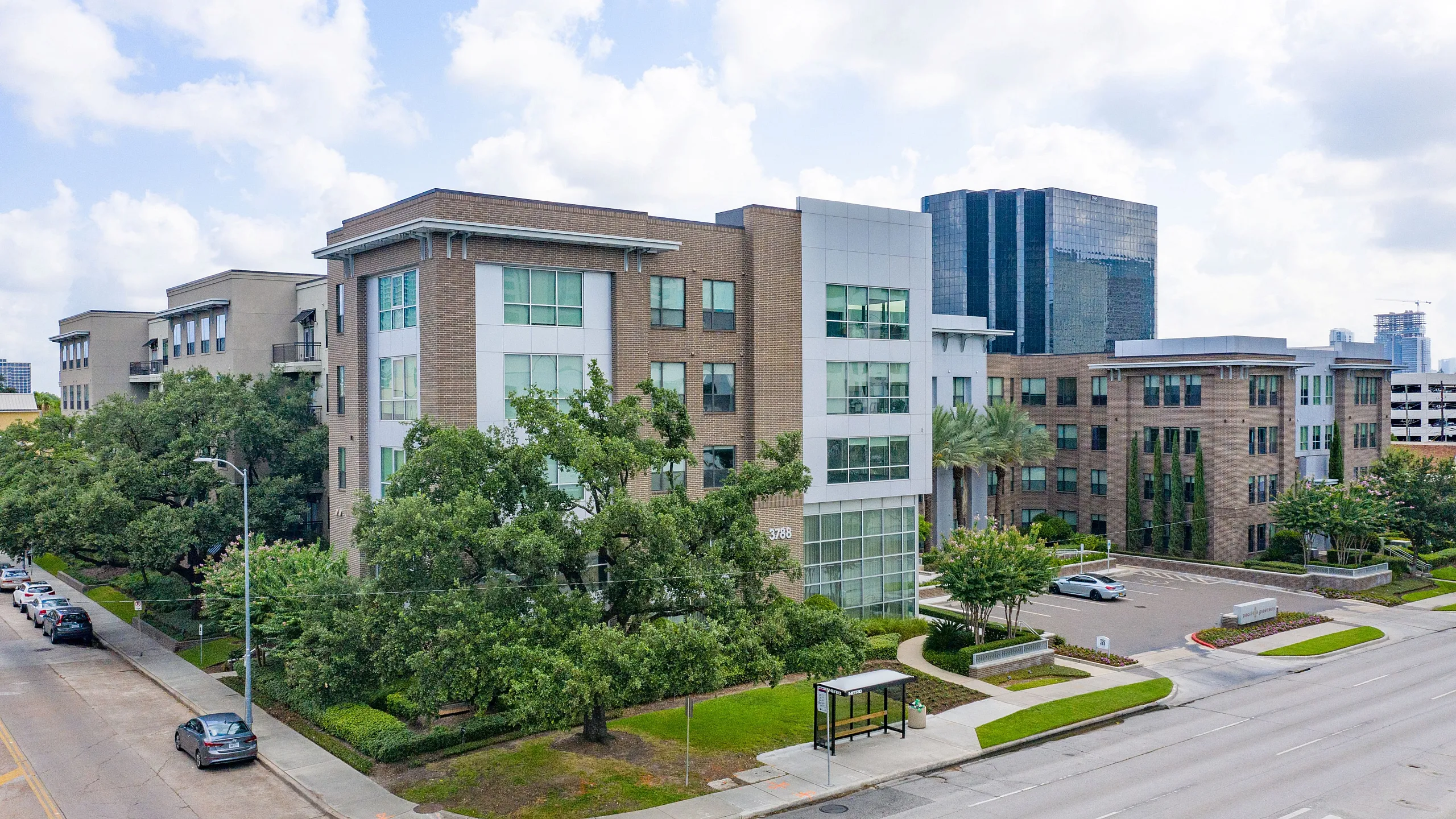 Modern urban apartment complex with stylish architecture, surrounded by lush greenery and a quiet street view.