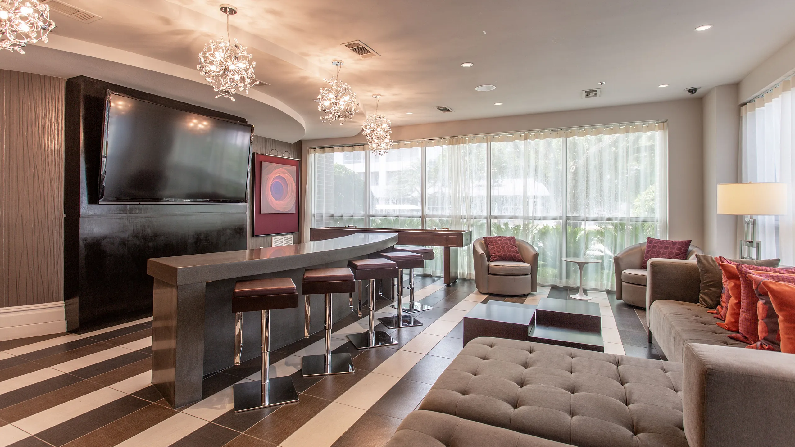 Elegant and modern living room with stylish lighting, large wall-mounted TV, and cozy seating area by a sunlit window. Perfect for relaxation and entertainment.