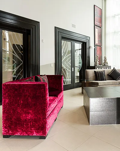 Elegant living room featuring a bold red velvet sofa, modern stone fireplace, and chic glass doors with stylish d&eacute;cor.