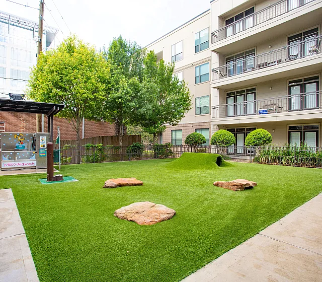 Charming apartment complex featuring a vibrant pet-friendly outdoor space with lush greenery and a modern dog wash station.