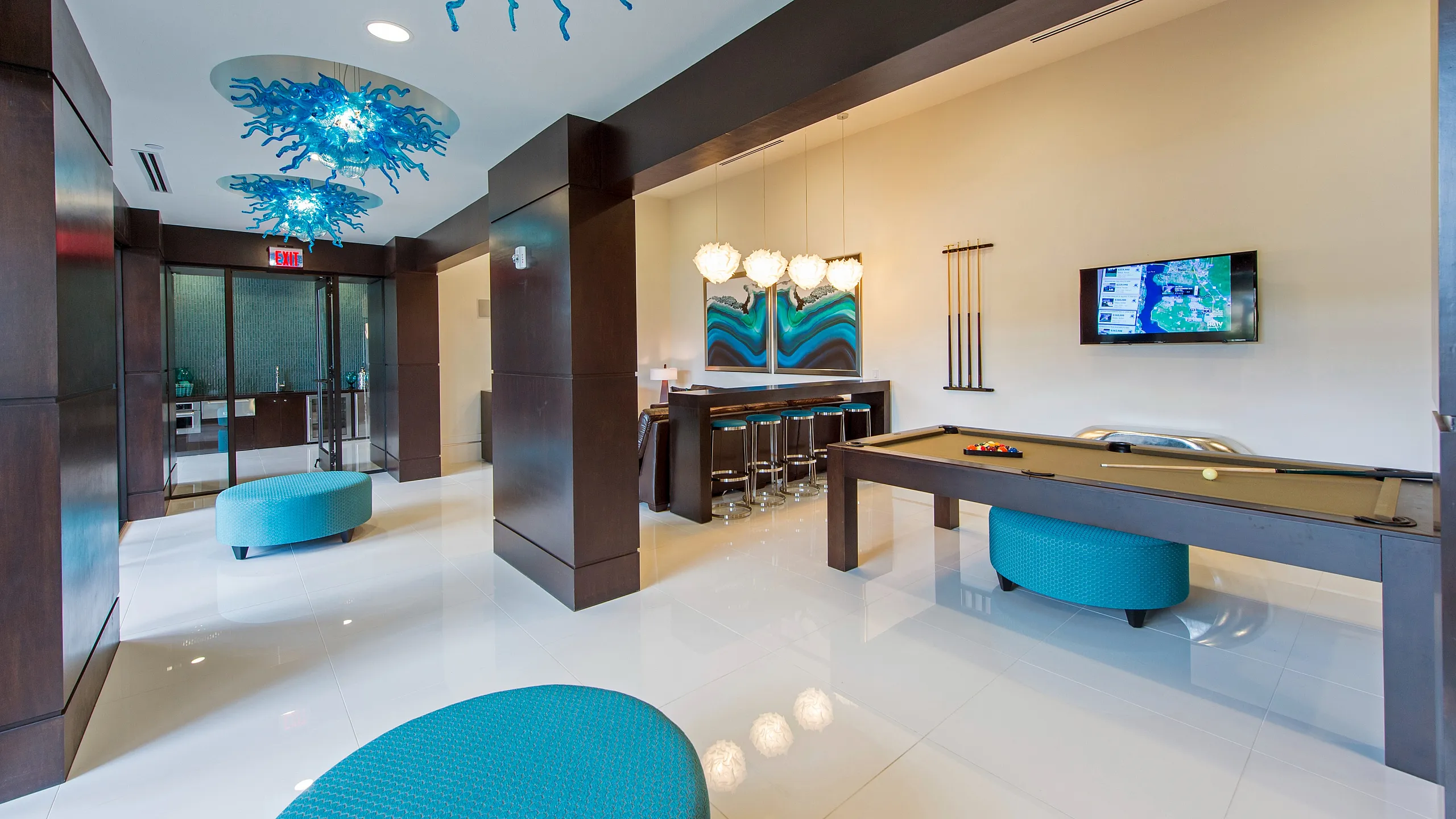 Luxurious modern lounge with striking blue light fixtures, sleek pool table, and sophisticated bar area.