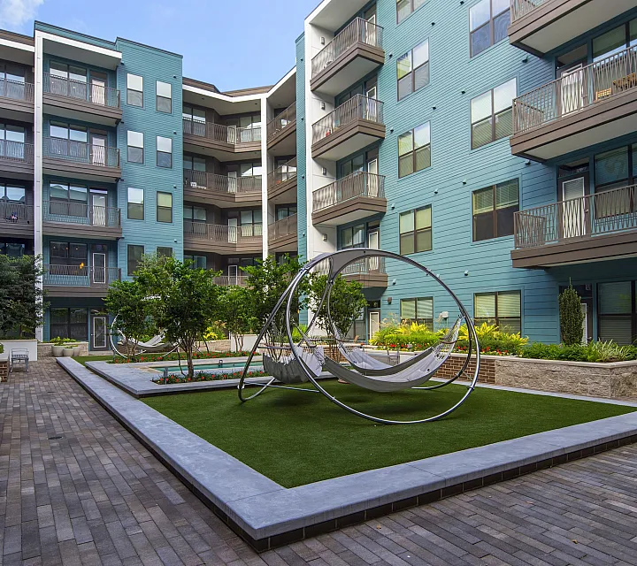 Chic urban apartment courtyard with modern hammocks and lush green landscaping, surrounded by elegant multi-story balconies.