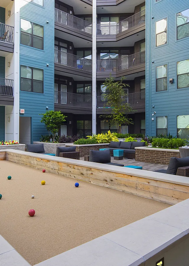 Modern apartment courtyard featuring a bocce ball court, elegant seating areas, and lush greenery, perfect for relaxation and social gatherings.