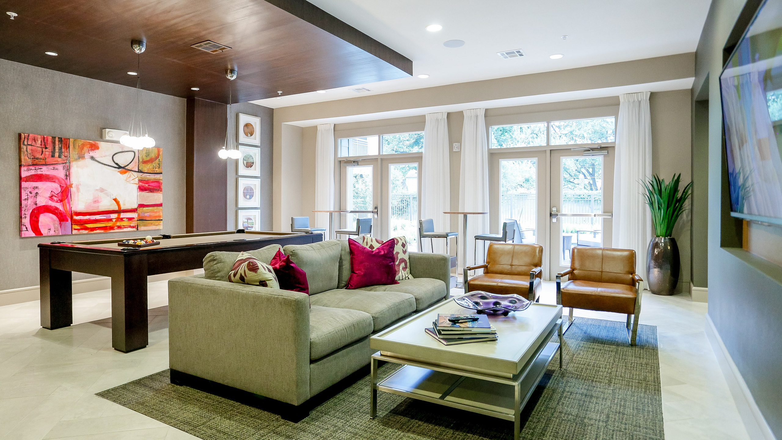 Chic apartment lounge featuring modern decor with vibrant artwork, comfortable seating, and natural light streaming through large windows.