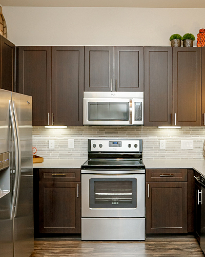 Modern kitchen with sleek stainless steel appliances, dark wood cabinetry, and elegant pendant lighting.