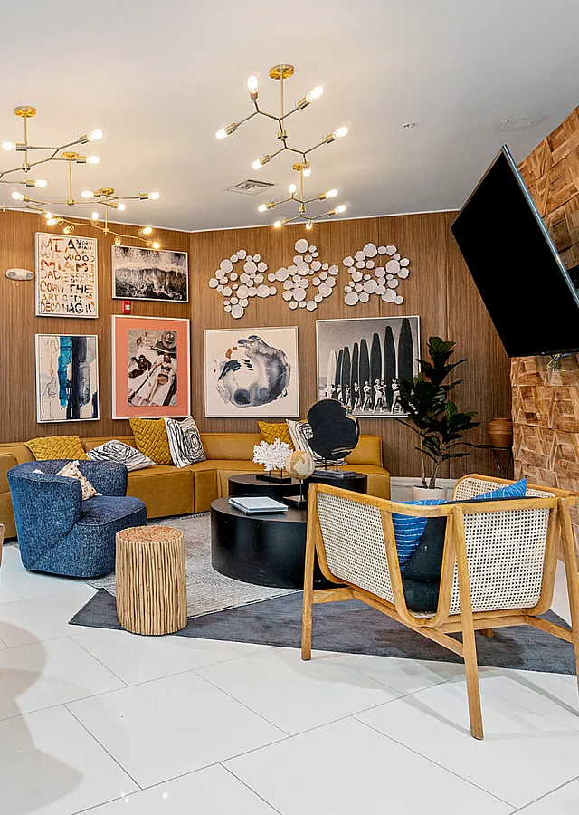 Inviting modern lounge area with cozy seating, eclectic wall art, and chic lighting in warm, welcoming tones.