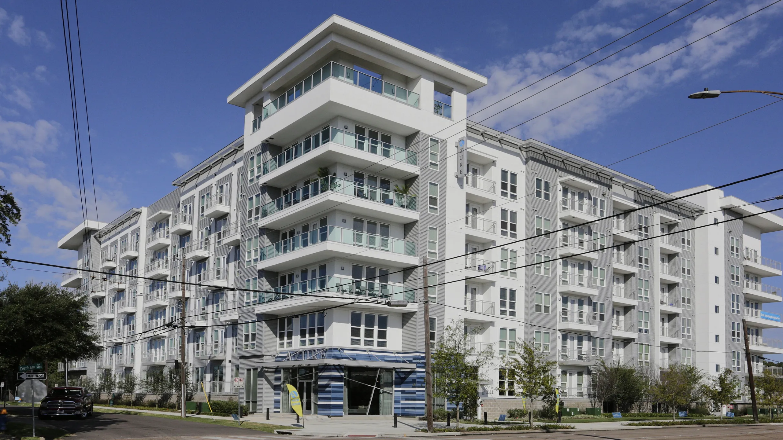 Elegant modern apartment building with spacious balconies and contemporary design set against a clear blue sky.