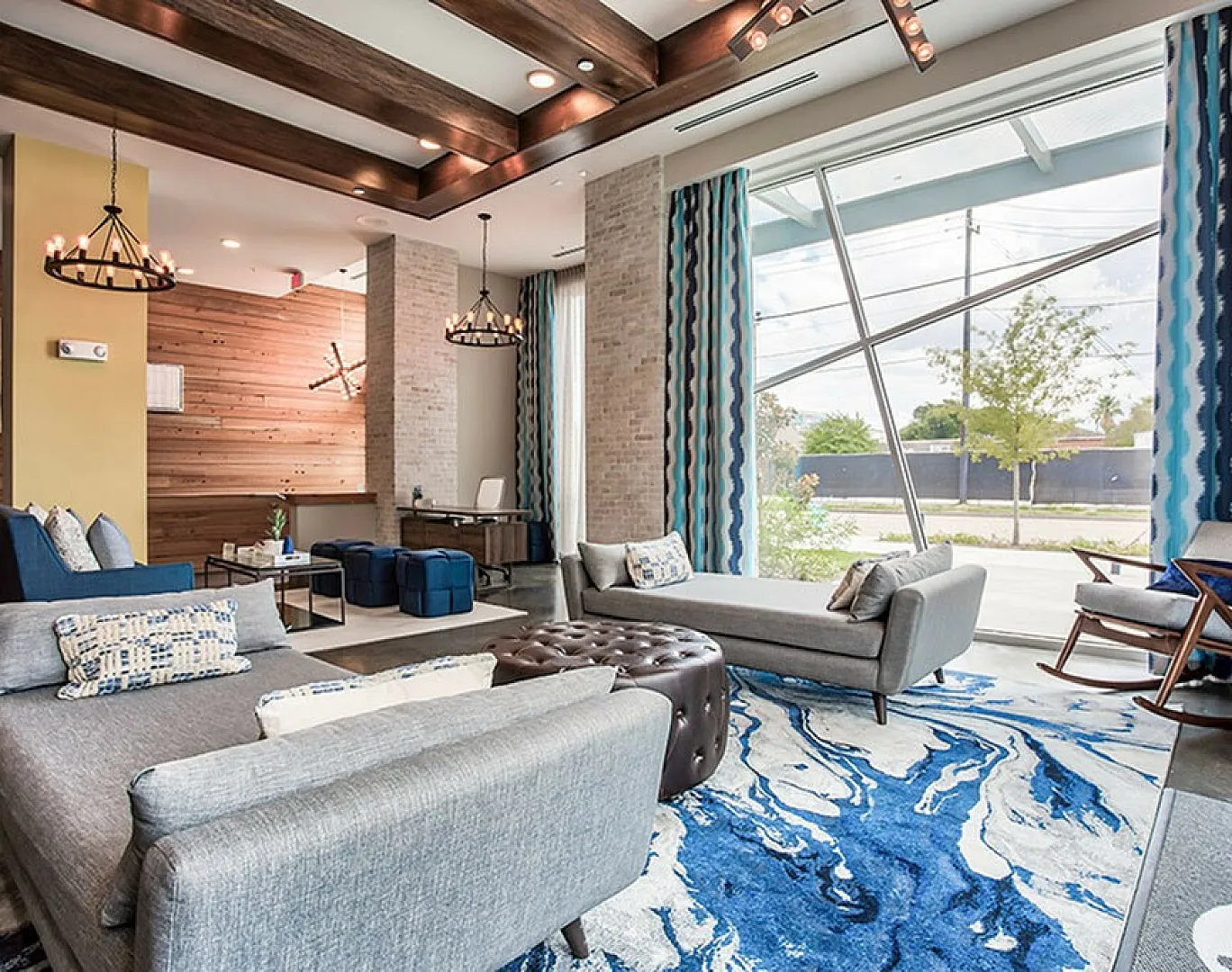Modern living room with chic furniture, large floor-to-ceiling windows, and stylish lighting fixtures, offering a bright and inviting space.