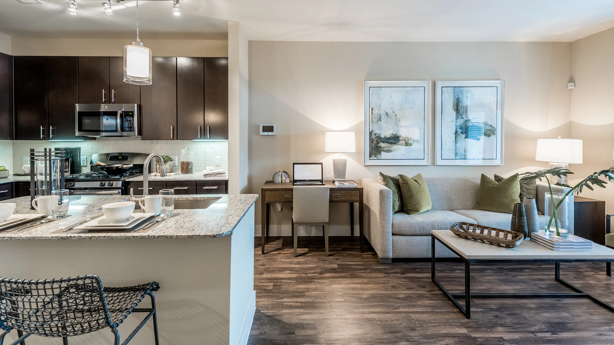 Modern open-concept apartment living room with sleek kitchen, elegant dining area, and cozy workspace, featuring contemporary decor and stylish furnishings.