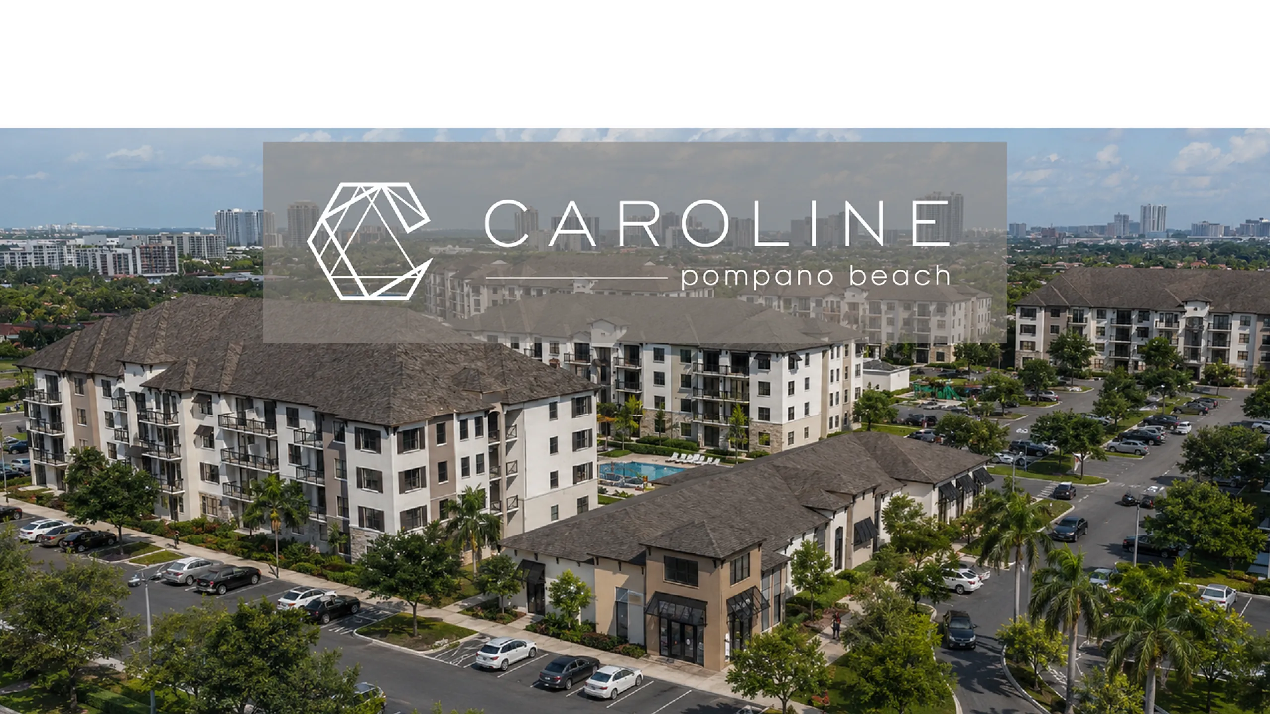 Aerial view of the elegant Caroline Pompano Beach apartment complex, featuring modern buildings, lush greenery, and a central swimming pool.