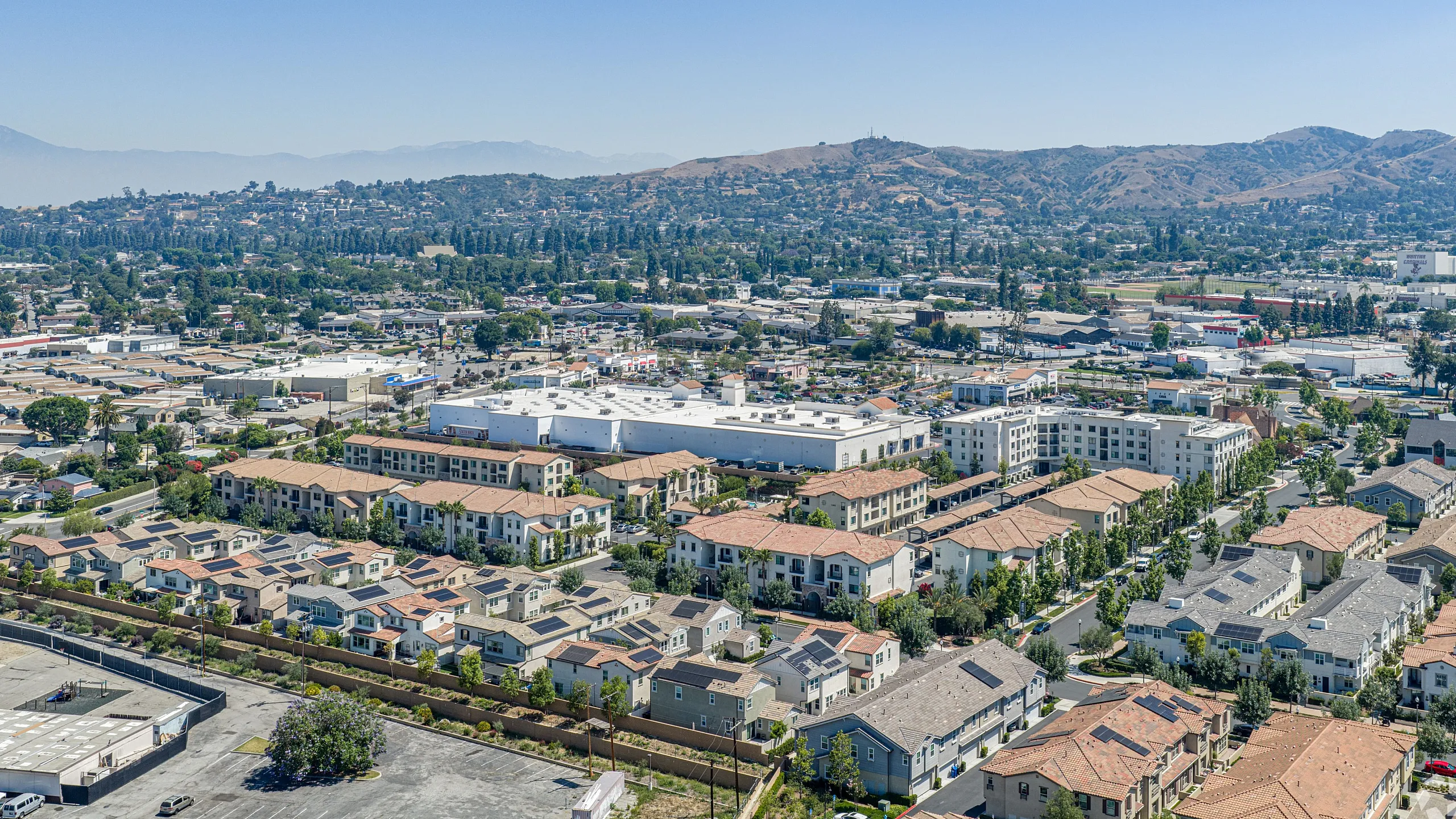 Stunning aerial view of a tranquil suburban neighborhood with charming homes and lush greenery surrounded by scenic hills.