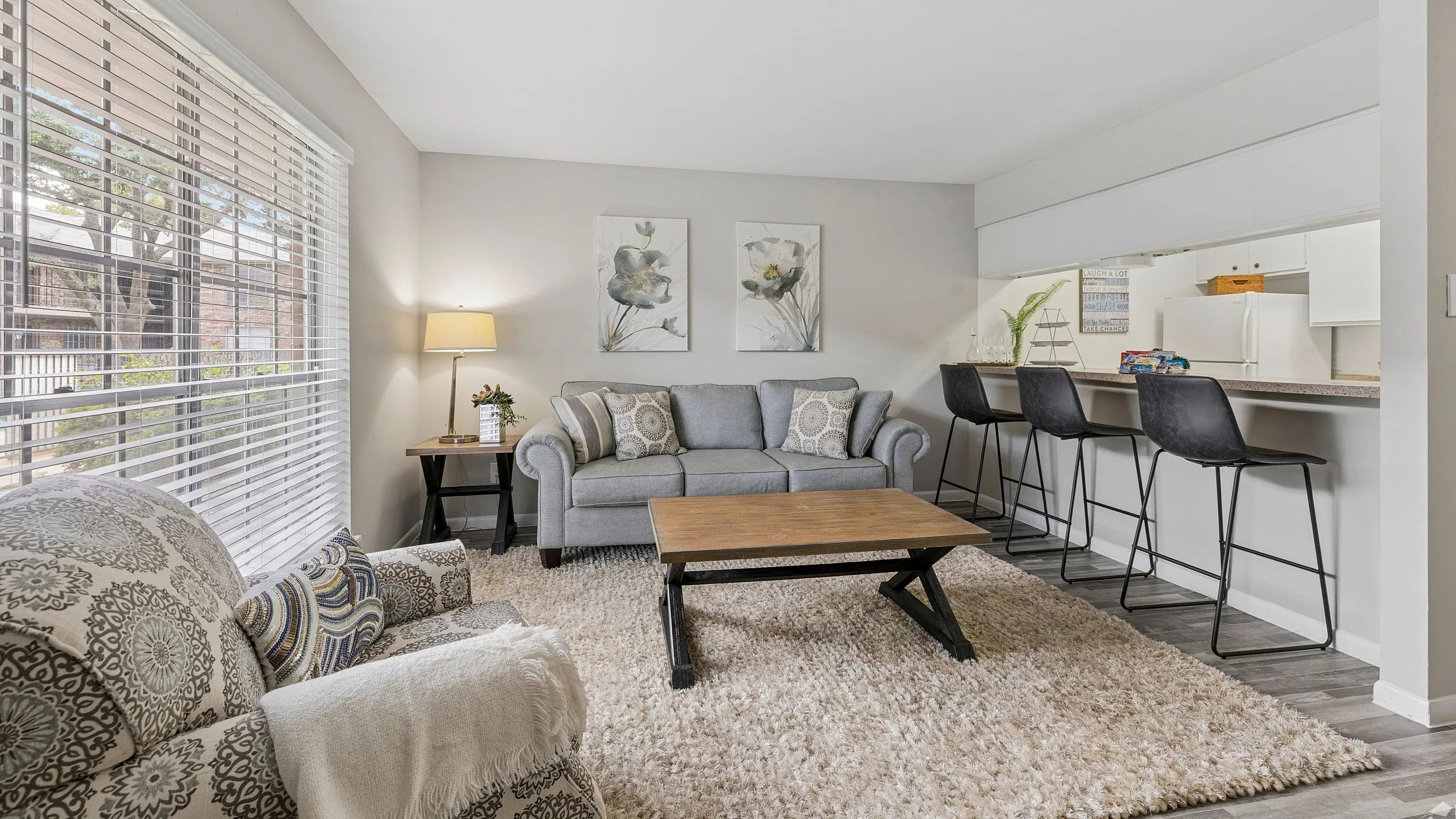 Inviting living room with plush seating, stylish decor, and a bright, airy atmosphere. Features a cozy sofa, elegant armchair, and breakfast bar with modern stools.