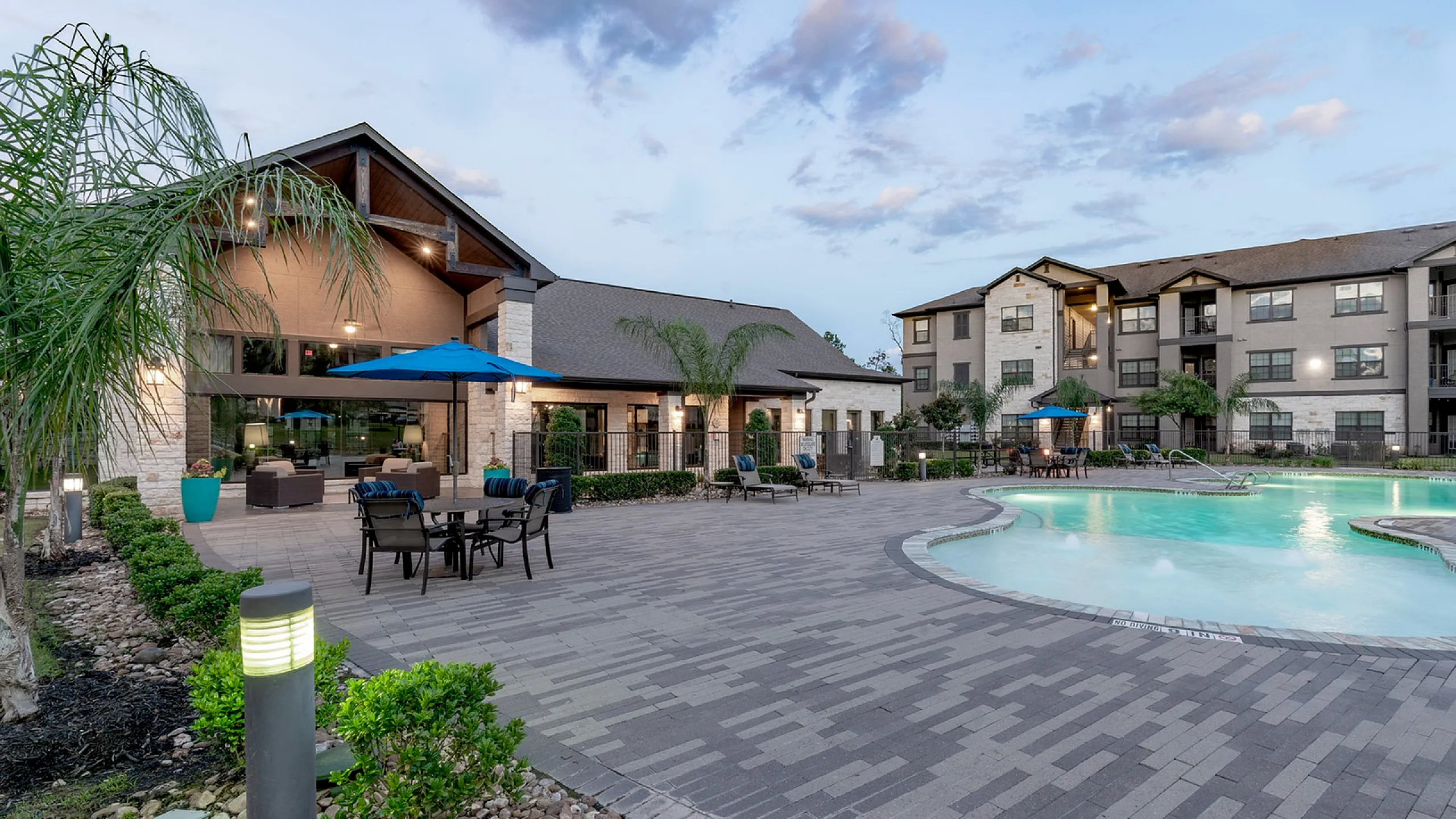 Resort-style pool and clubhouse at twilight with patio seating in Conroe, TX