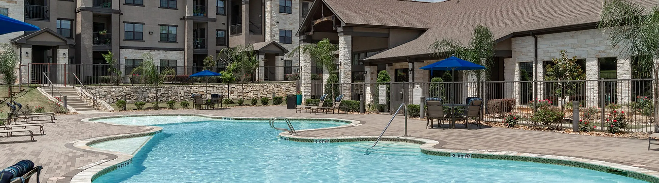 Pool with sun deck, cabanas, and three-story apartment buildings in Conroe, TX
