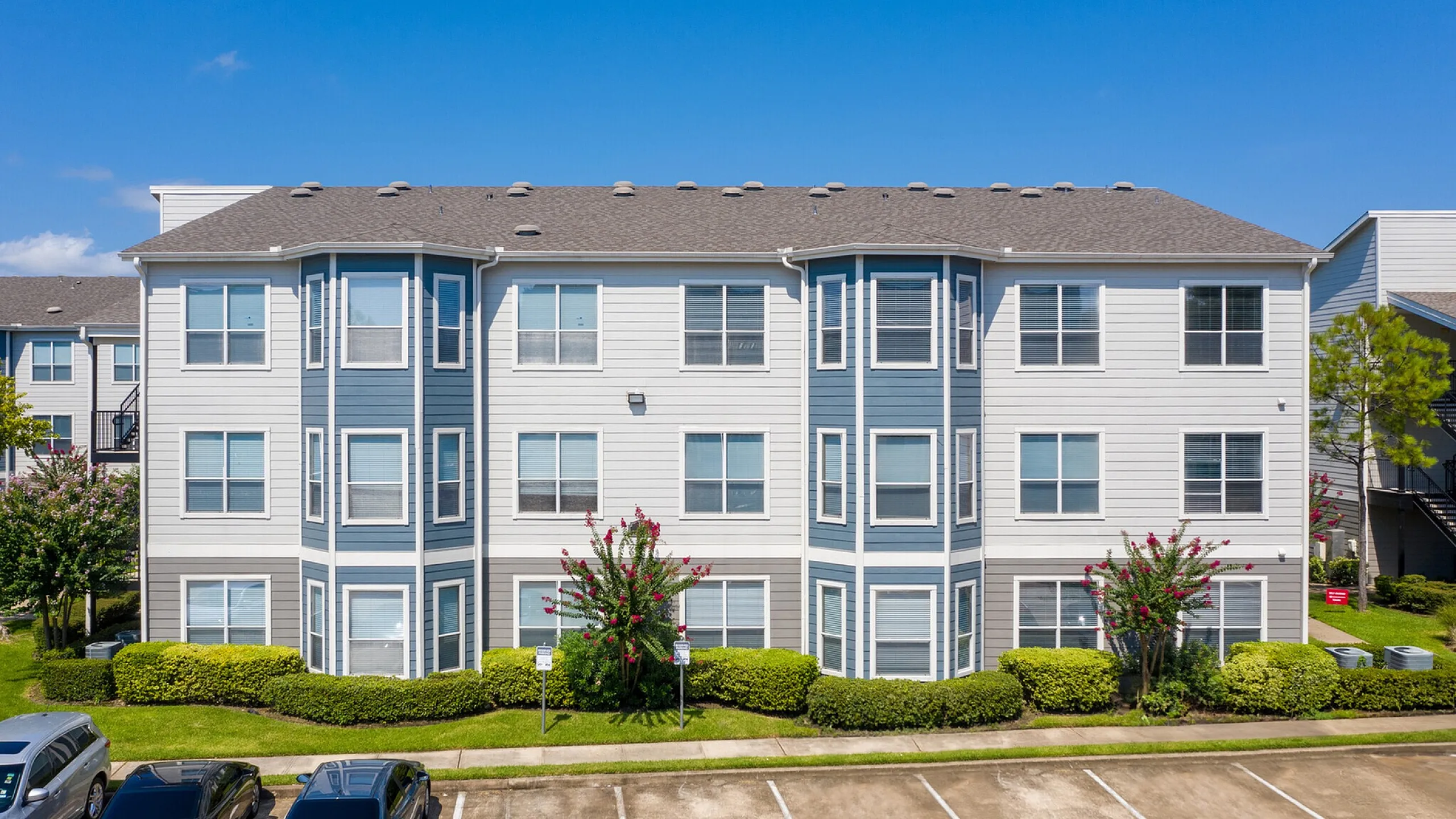 Three-story apartment building with bay windows, landscaping and parking, Houston, TX