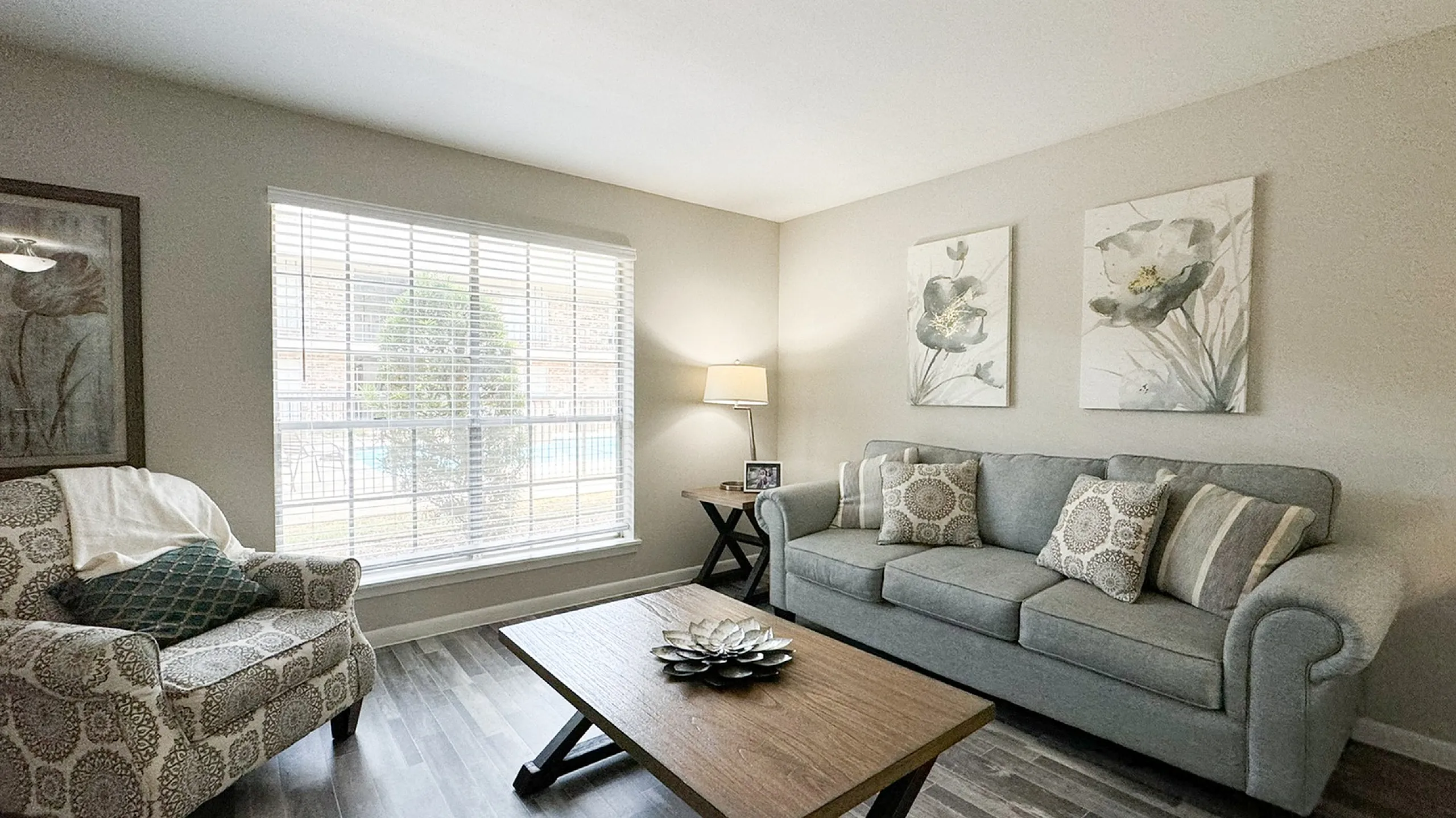 Living room with sofa, wood coffee table, wood plank flooring and window blinds