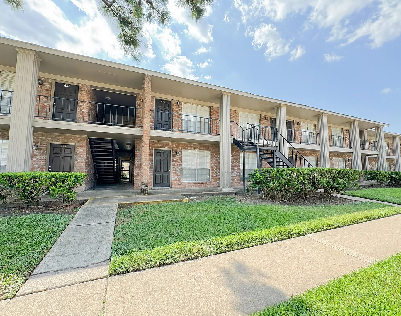 Two-story brick building with balconies, exterior stairs, hedges and lawn, Memorial City, Houston TX