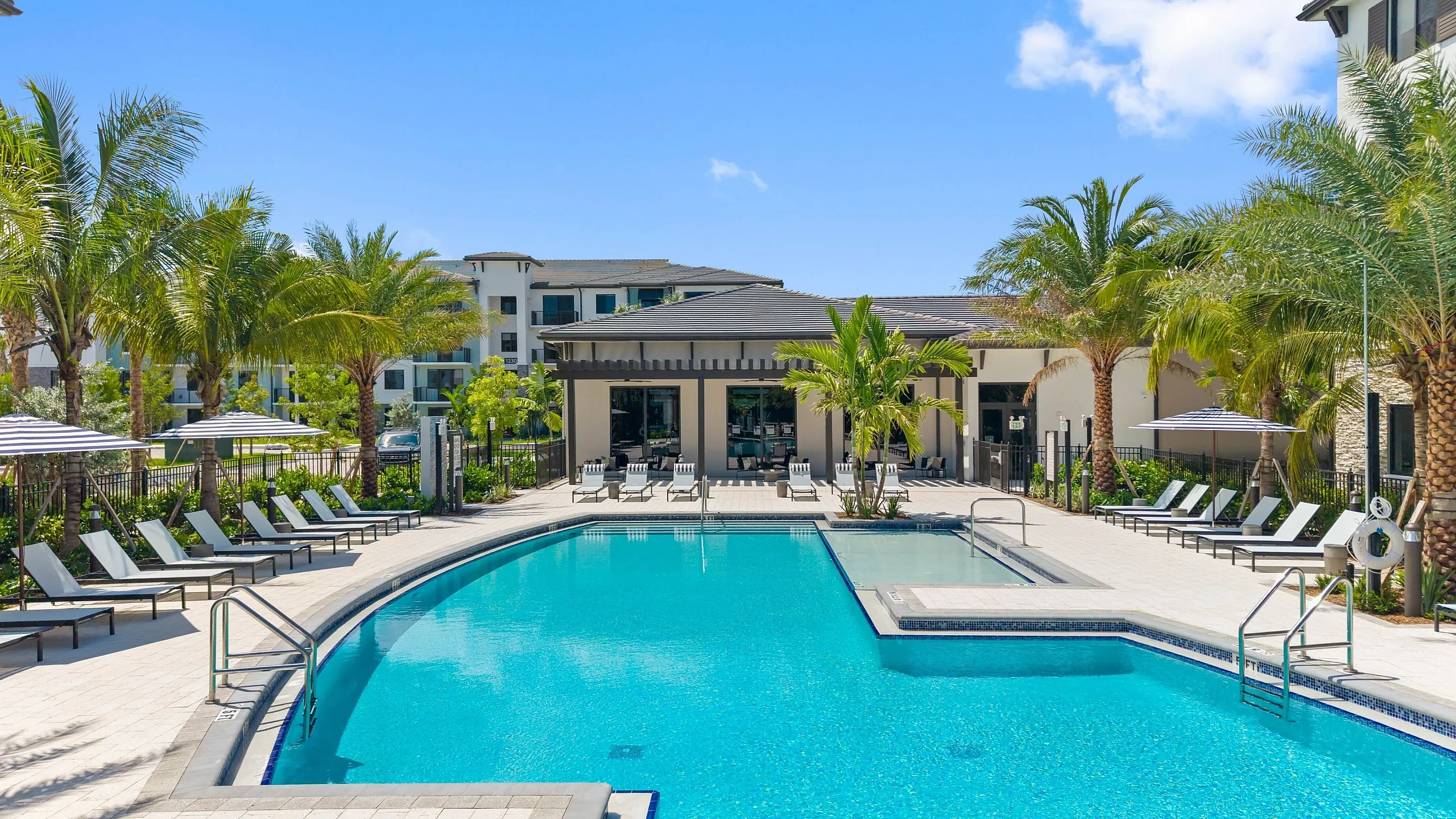 Resort-style pool with lounge chairs and palm trees at Caroline Pompano Beach