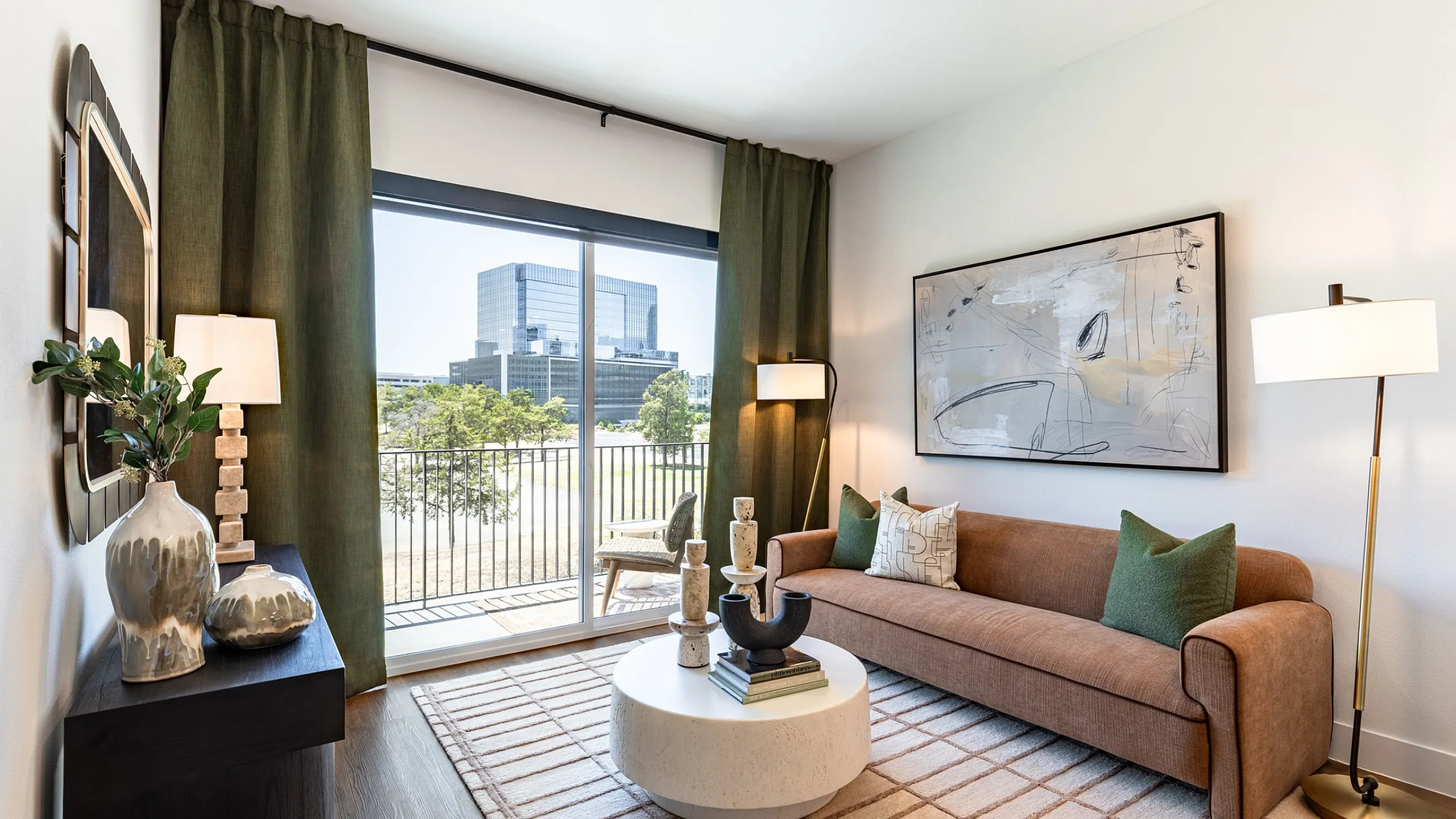 Living room with sofa, round coffee table, wood plank flooring and sliding door to a balcony