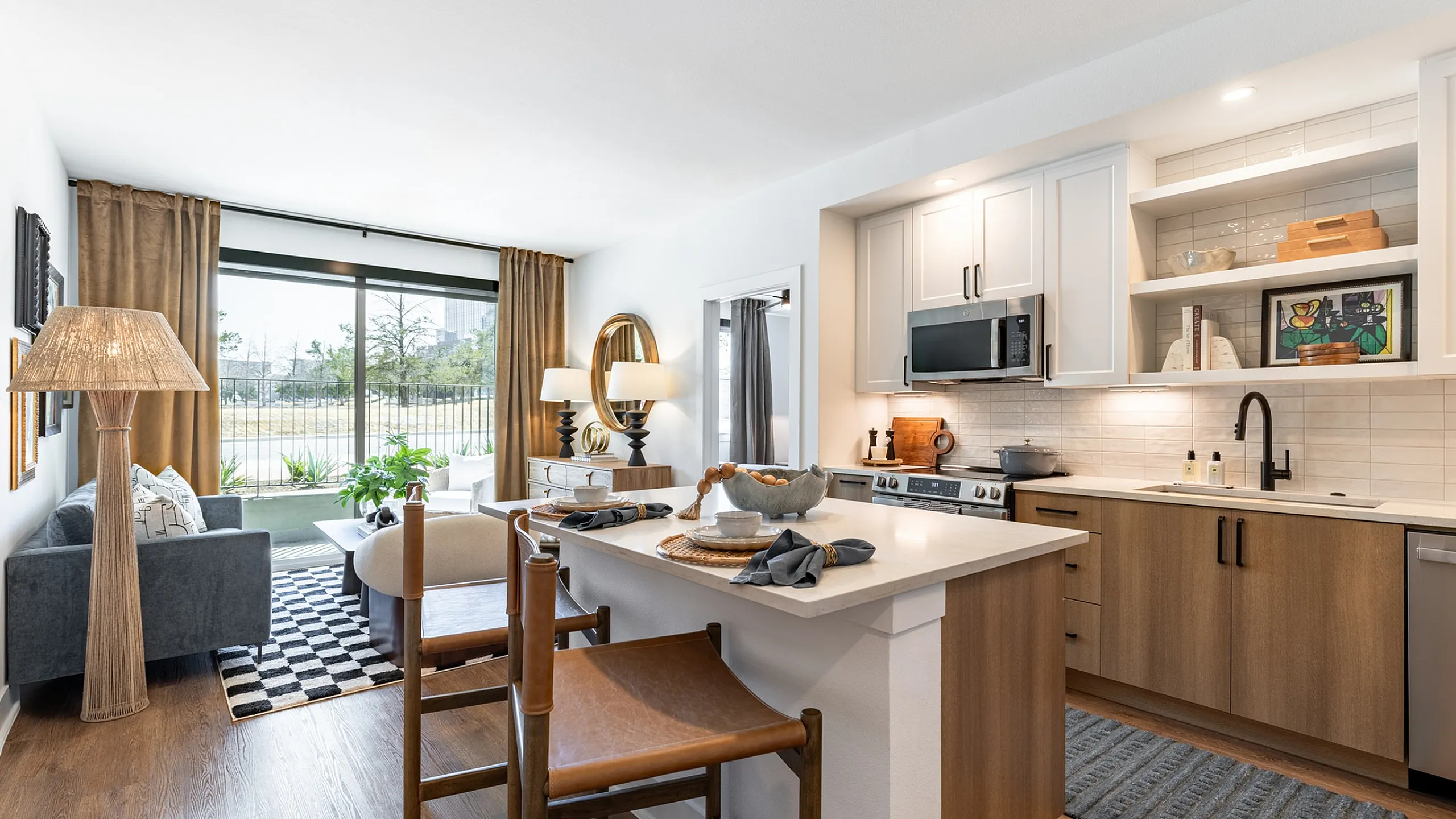Kitchen with island and stools, white counters, tile backsplash, stainless steel appliances and wood plank flooring