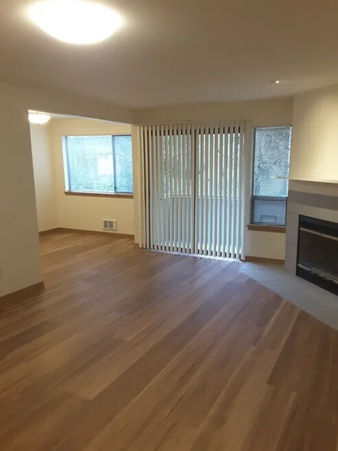 Inviting living space with elegant wood flooring, cozy fireplace, and large windows offering abundant natural light.