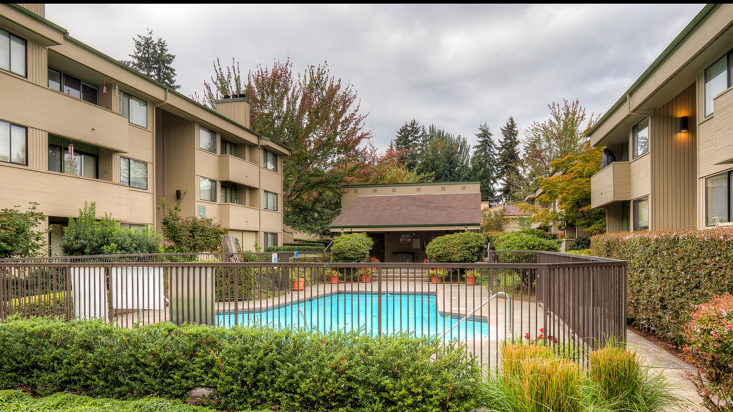 Charming apartment complex featuring a refreshing outdoor pool surrounded by lush greenery and inviting walkways.