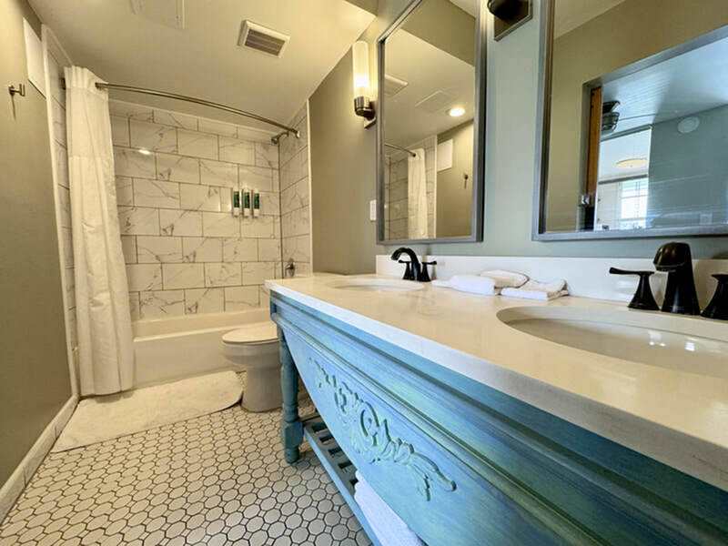 Elegant bathroom featuring a stylish double vanity, marble-tiled shower, and chic hexagon floor tiles.