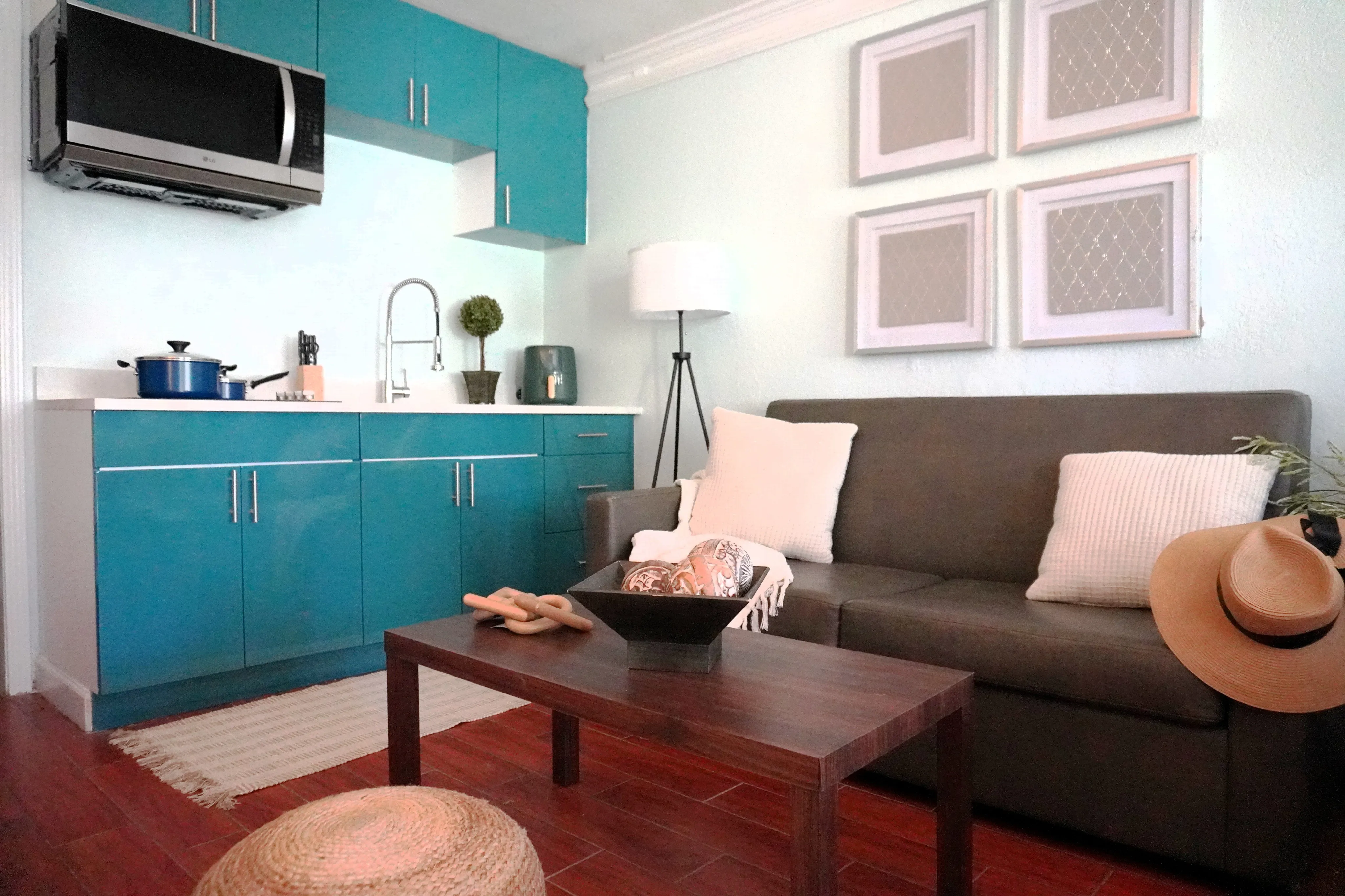 Charming apartment interior with vibrant teal cabinets, a comfy gray sofa, and stylish decor, perfect for modern living.